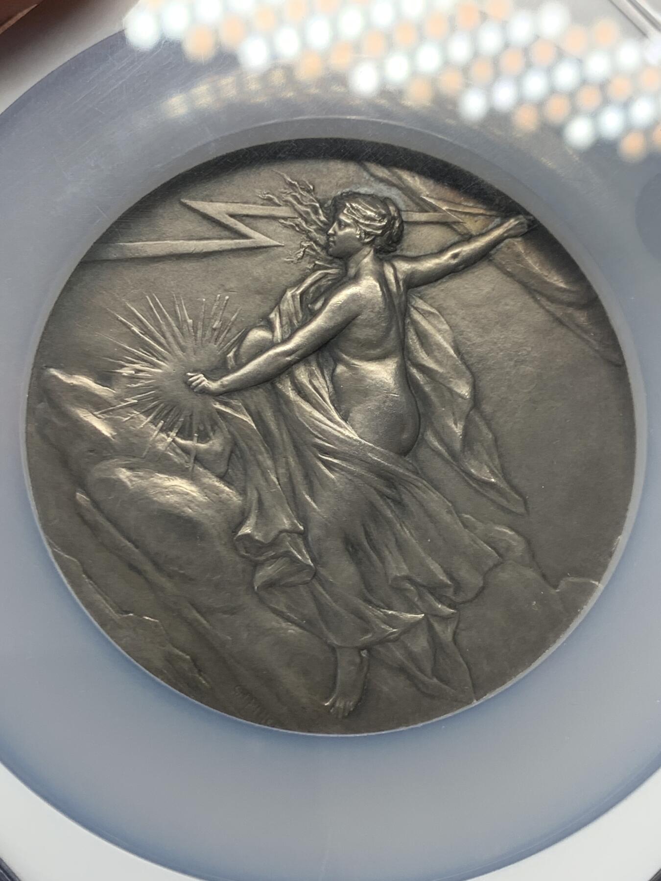 《竞宝斋》立夏专场特拍 （第2-1场）全场顺丰包邮 265场 NGC MS63 法国电力女神大银章，和法兰西银行百年、突尼斯开港都是68mm的精品大章，作者皮列是骑马鹰洋的雕刻师，法章名家。正面的裸身女神丰腴立体，背面是景观，一章两面都是精品。这个品种63高分罕见，章牌爱好者必冲。