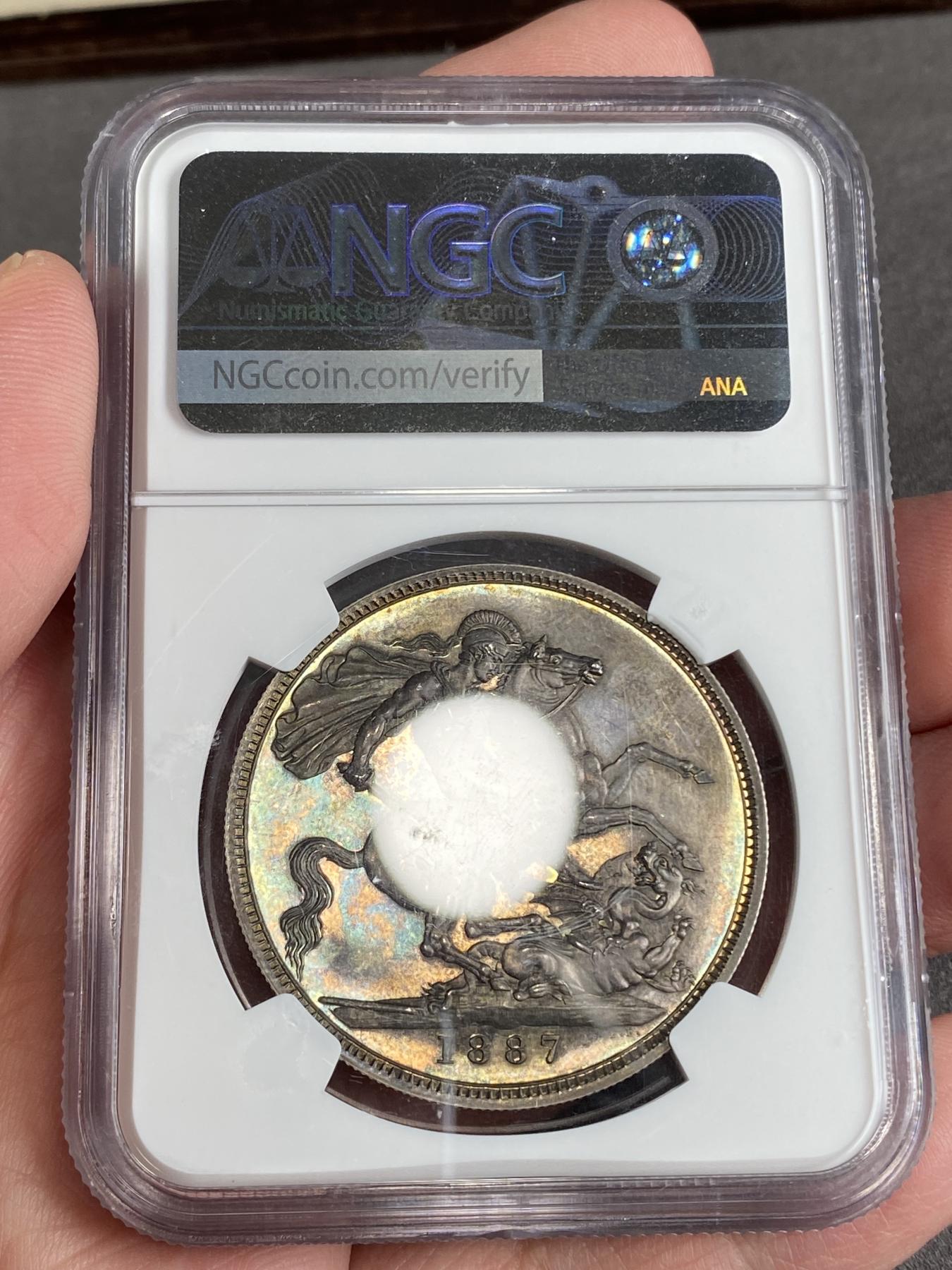 万国钱币拍卖第025期（槐月至·百币艳） NGC PF64 1887英国维多利亚高冠马剑精制克朗 发行量1084枚，在补涨一轮后依然是价格最为亲民的英国19世纪精制克朗，与爱七Matte和乔五精制木马相比依旧保留了古典时代的韵味，而精制工艺也达到了巅峰水准。英国的潮湿气候造就此枚马剑的双面欧陆五彩，在深度镜面的底板上反射出了日不落帝国最后的余晖。