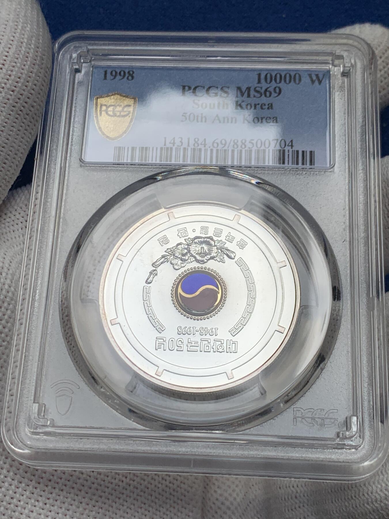 《竞宝斋》第279场- 周日，周一 ，周二3场连拍 （全场包邮） PCGS MS69 少见韩国银币 附带原包装和证书 1998韩国10000韩元 建国50周年纪念银币 中间有珐琅彩 有点致敬朝鲜大东珐琅的意味 这一枚是P盒唯一冠军分 珐琅彩很难保存 工艺非常好 币面极干净