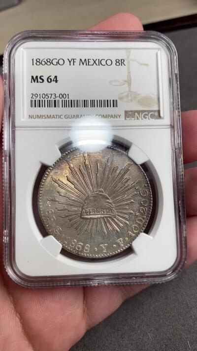 万国钱币拍卖第028期（花前月下●同享良章美币） NGC MS64 1868年墨西哥鹰洋8R银币 梦幻彩虹包浆，实物绝美。底板和打制都是64分中的佼佼者。老评级号换的新盒子，品质保证。