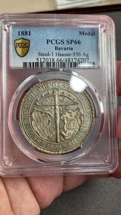 万国钱币拍卖第028期（花前月下●同享良章美币） PCGS SP66 1881年德国巴伐利亚慕尼黑联邦射击节大银章 顶级品质名誉品种，稀有精制镜面浮雕状态，正面：狩猎弓弩，巴伐利亚徽章，慕尼黑徽章，枝叶纹理雕刻清晰。背面：德意志帝国王冠鹰，设计繁复华丽，羽毛丝丝入扣，细节极佳。整章在静态中创造出一种运动感，独树一帜的设计，极其经典的德射品种，实物更加惊艳。