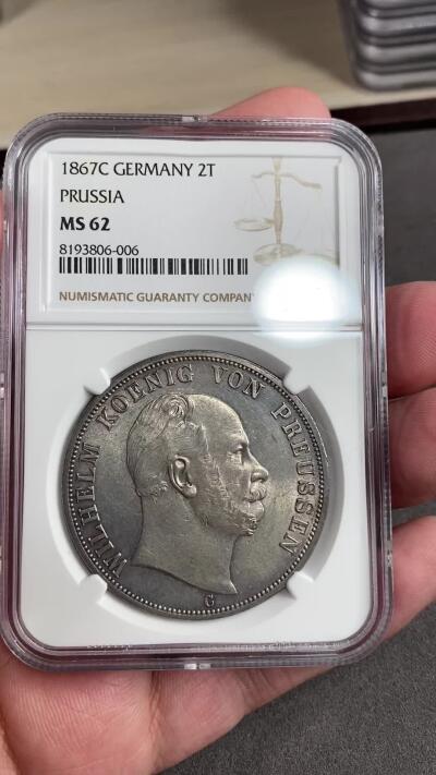 万国钱币拍卖第028期（花前月下●同享良章美币） NGC MS62 1867年德国普鲁士威廉一世2泰勒大银币 经典的C法兰克福厂 十字转光配上原味原始状态的币面 清新淡雅的状态令人着迷