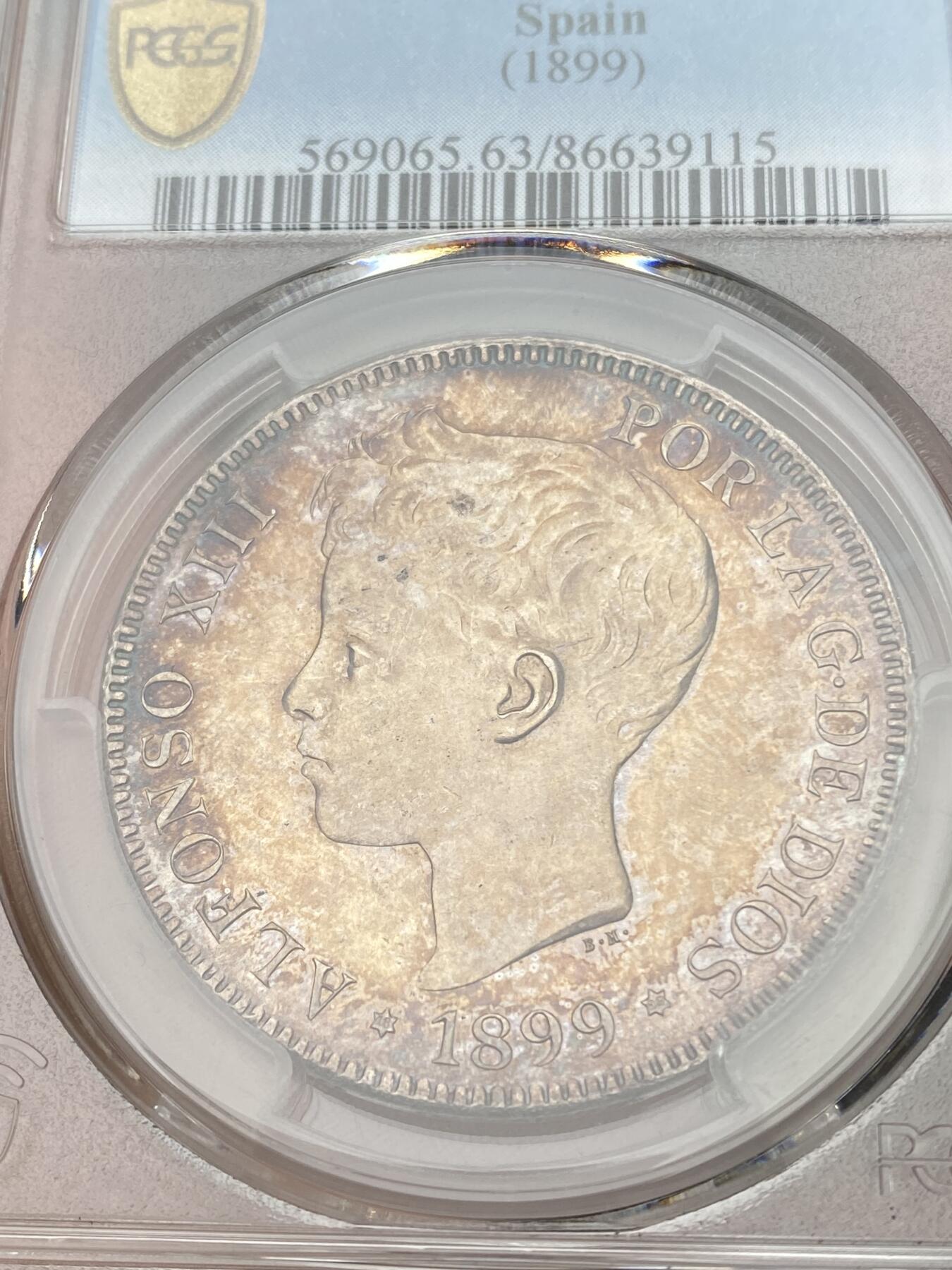 万国钱币拍卖第028期（花前月下●同享良章美币） PCGS MS63 1899年西班牙5比塞塔大银币 经典男童设计，海格力斯双柱。通体原味虹彩包浆，车轮光打制优异底板佳。实物非常漂亮，远超白板的视觉享受，也没有一般63的伤痕累累。评分略微保守，作为流通币保存状态相当不错。相对少见的年份，值得收藏的热门西班牙大银。