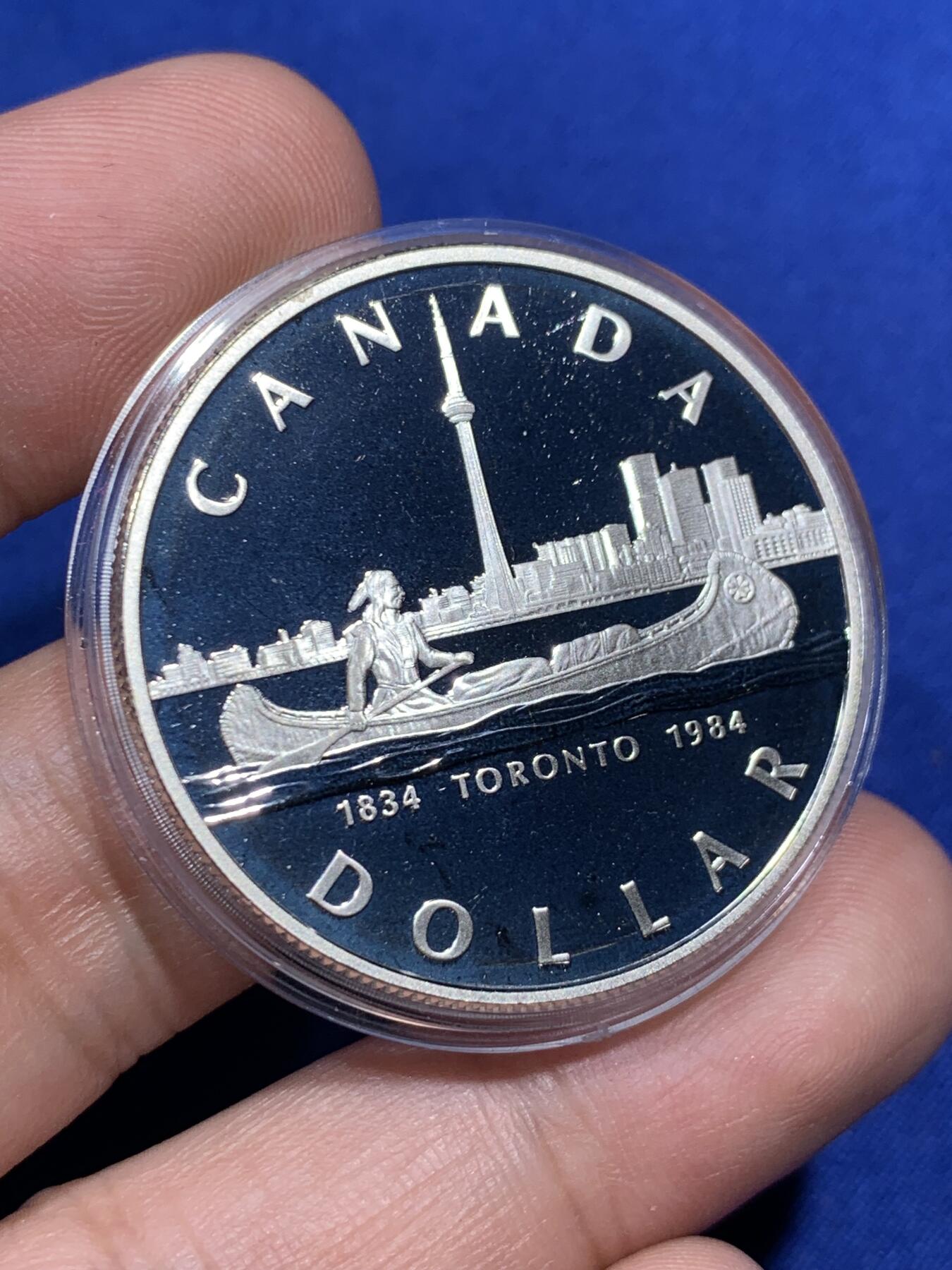 《竞宝斋》第290场- 周日，周一，周二 3场连拍 （全场包邮） 1984年加拿大多伦多市成立100周年纪念精制银币 正面为伊丽莎白二世女王年轻时右向胸像 背面为水面划船的印第安人背景为多伦多轮廓