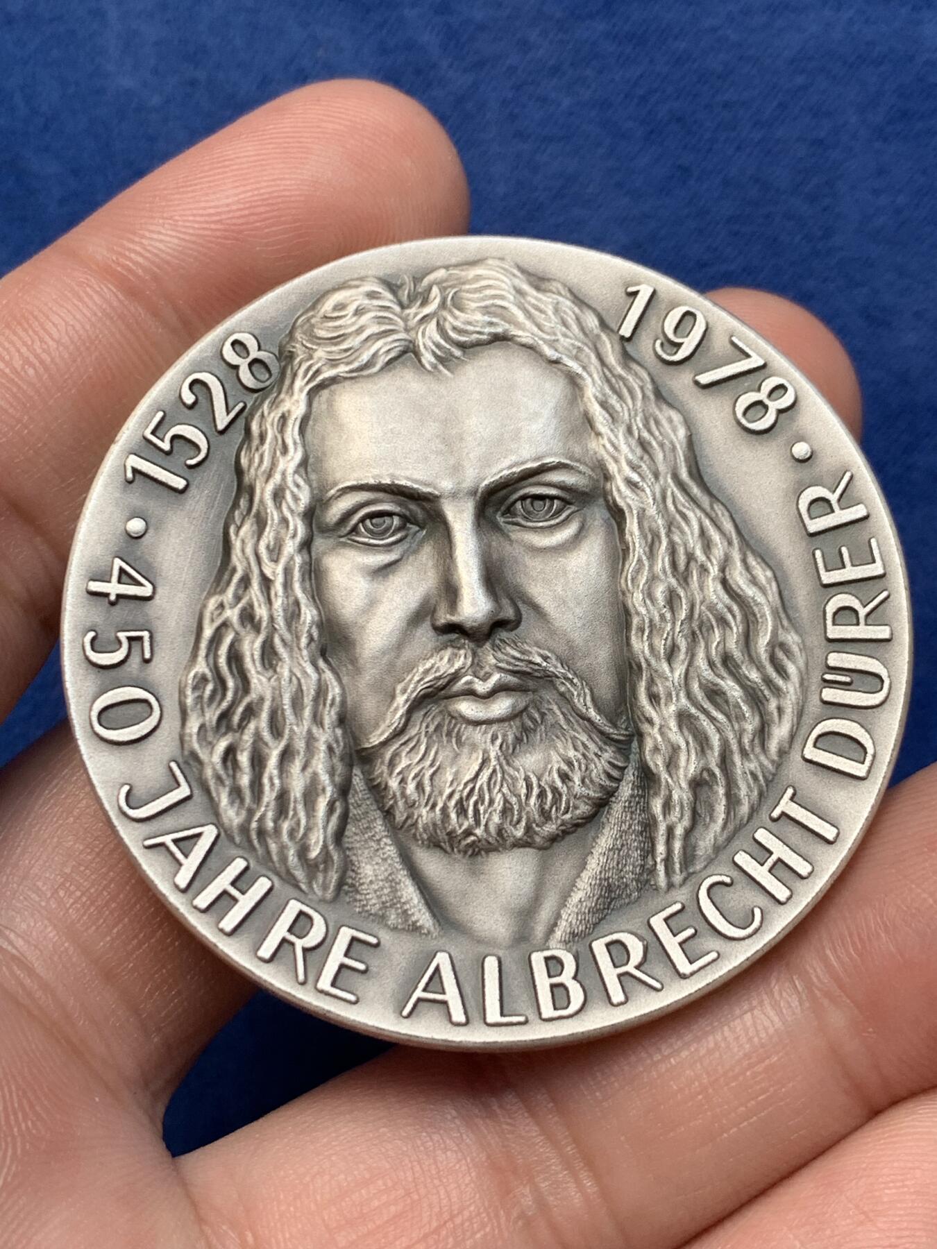 《竞宝斋》第294场- 周日，周一  2场连拍 （全场包邮） 1978年德国艺术家，阿尔布雷特•丟勒（Albrecht Direr，1471年一1528年），逝世450周年银章，他生于纽伦堡，是德国著名画家、版画家及木版画设计家。直径49.5mm；纯银；重60,65克。主要作品有《启示录》《基督大难》《小受难》《祈祷之手》《男人浴室》《海》《浪荡子》《伟大的命运》《亚当与夏娃》和《骑士、死神与魔鬼》等