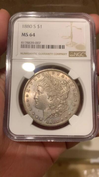 《竞宝斋》第294场- 周日，周一  2场连拍 （全场包邮） NGC MS64 美国1880-S 摩根1美元银币 一颗到位的1880年摩根，该特有的镜面底板，配合正面五彩包浆非常亮眼，尤其是背面带有一抹绚丽彩虹，摩根标准器，错过要后悔的状态。