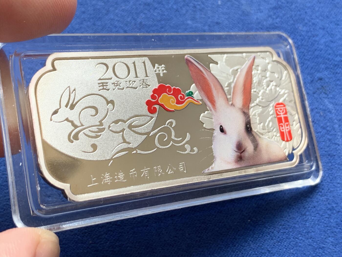 《竞宝斋》第297场- 周日，周一  2场连拍 （全场包邮） 彩银 2011年 中国 上海造币厂 兔年 30克大银条，最近银价7左右，一面是可怜的兔子和两只私奔月亮的玉兔，彩色兔子后面的牡丹花很立体，一面是体现上海接轨国际化lunar的新春快乐，花朵内部花蕊三只兔子围绕一起，有点曼岛的三条腿的感觉。