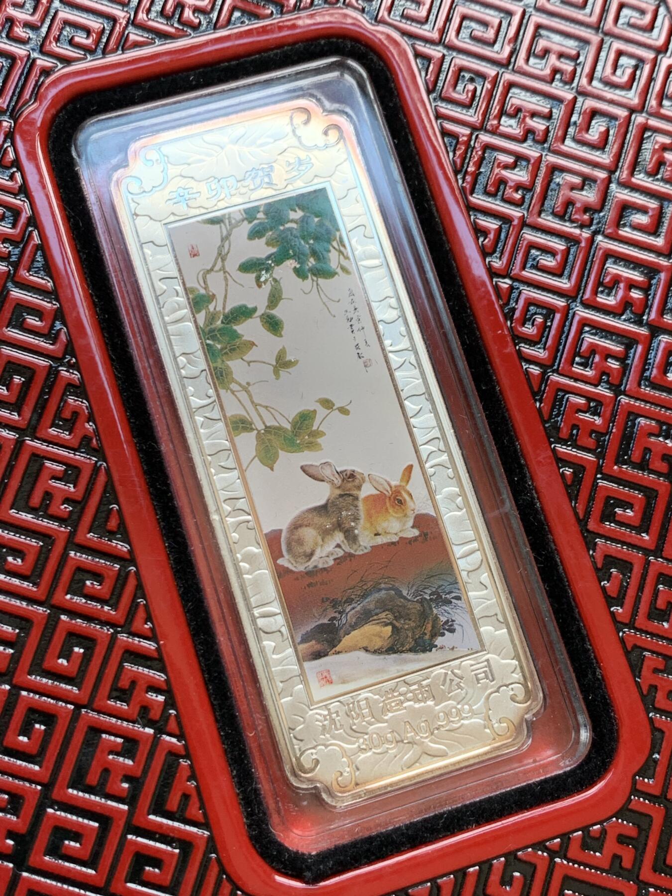 《竞宝斋》第297场- 周日，周一  2场连拍 （全场包邮） 彩银 2011年 中国 沈阳造币厂 兔年 30克大银条，贺岁宝泉高档包装，有朱红色台座，可摆桌面转运，原装盒证，一面是两只小兔晒恩爱脱单，一面是玉兔呈祥牡丹花富贵图。