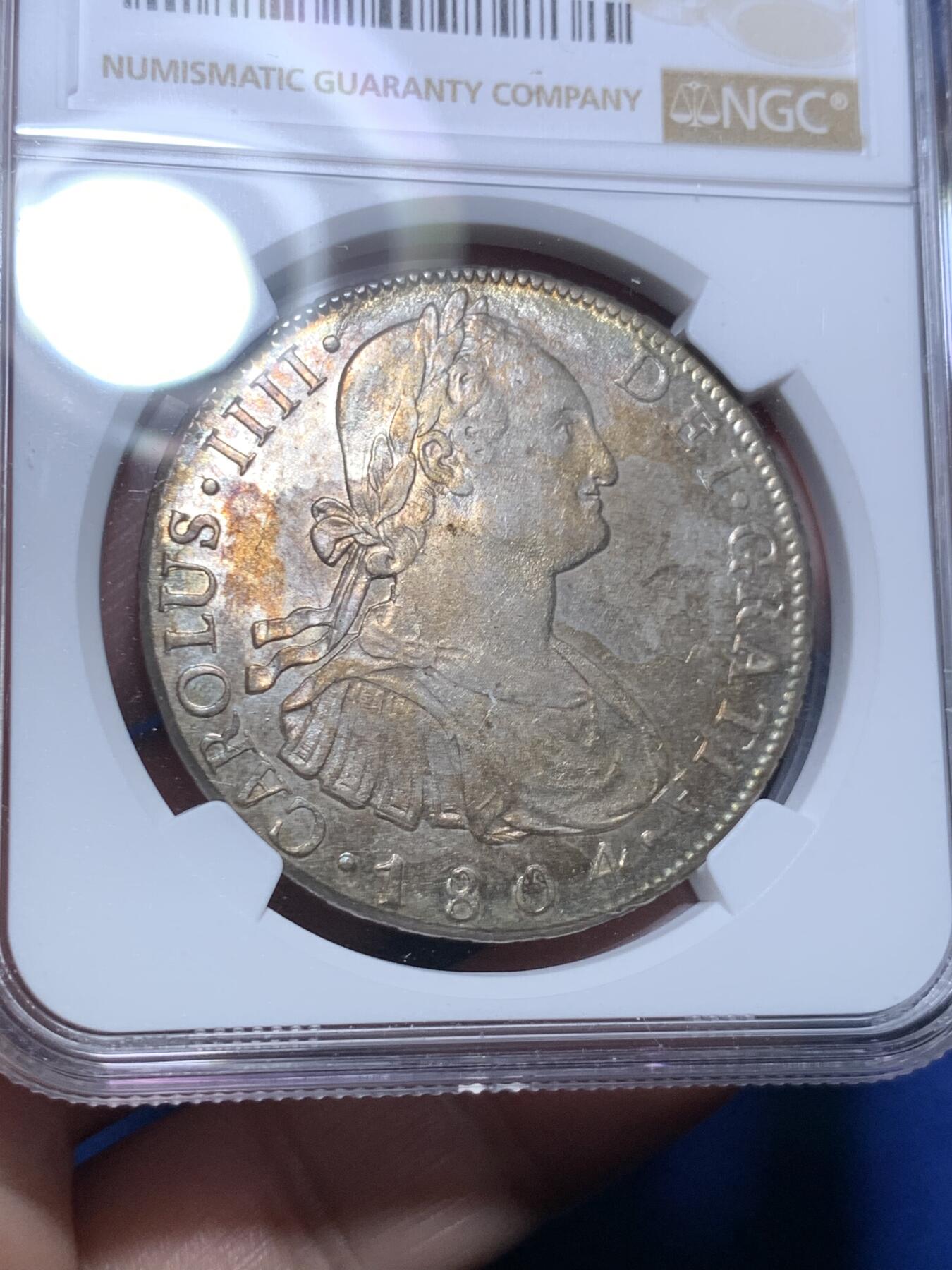 《竞宝斋》第298场- 周日，周一  2场连拍 （全场包邮） NGC AU58 玻利维亚1804年卡洛斯四世8里亚尔银币 高点细节具在，底板几近无痕 光感强烈 币面环状五彩黄油光包浆 非常漂亮，严重低评的一枚