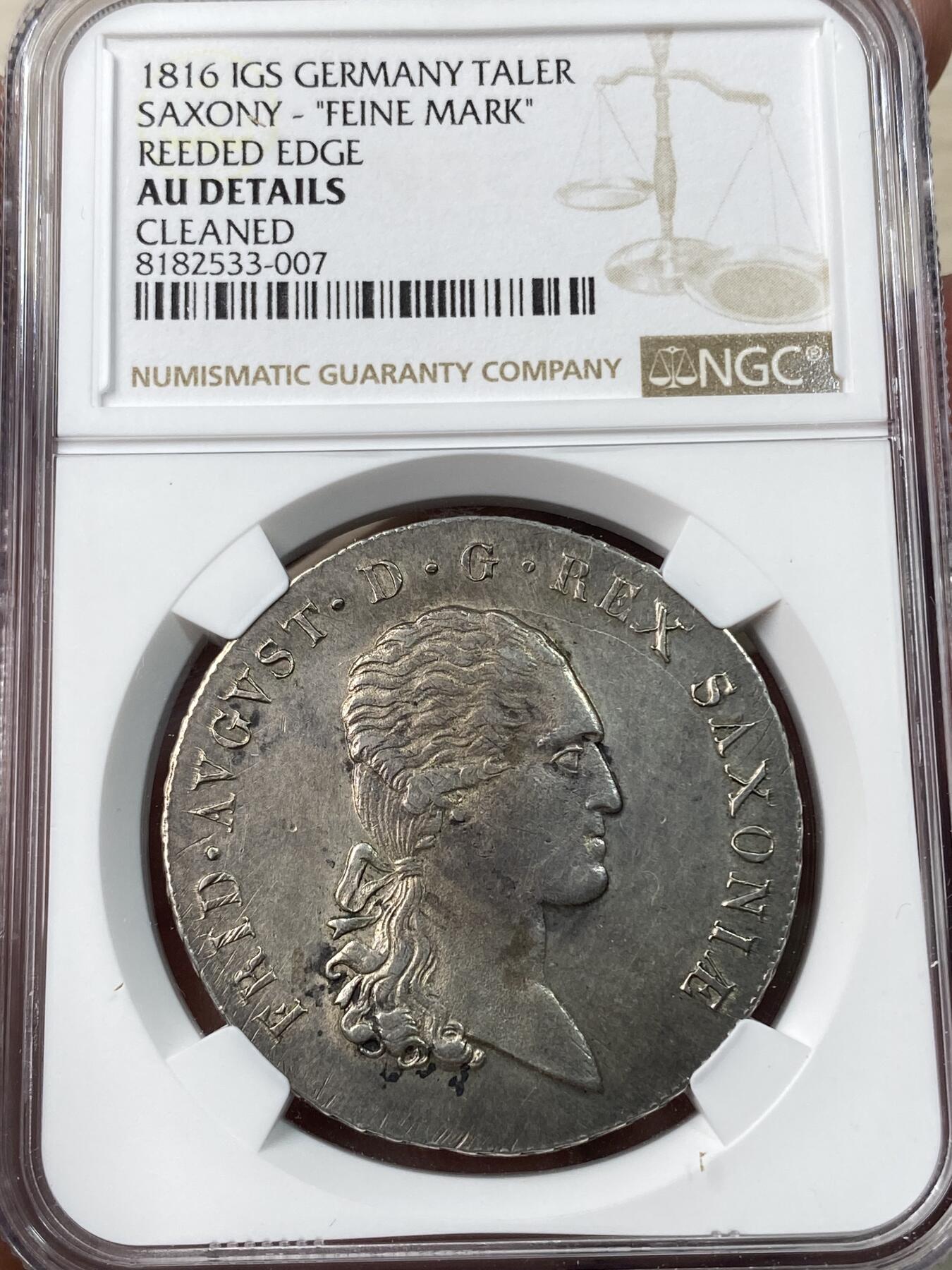 万国钱币拍卖第033期 NGC AUD 1816年德国萨克森花边协定大泰勒，重 28.0644g，纯度 83.3%，直径39mm。正面为弗雷德里克奥古斯都一世头像。背面圈铭：十枚兑一科隆马克银。此为倒数第二个发行年份，数量较为稀少，也是发行期间，唯一头像胸口位置靠近币缘的年份，俗称larger bust。
