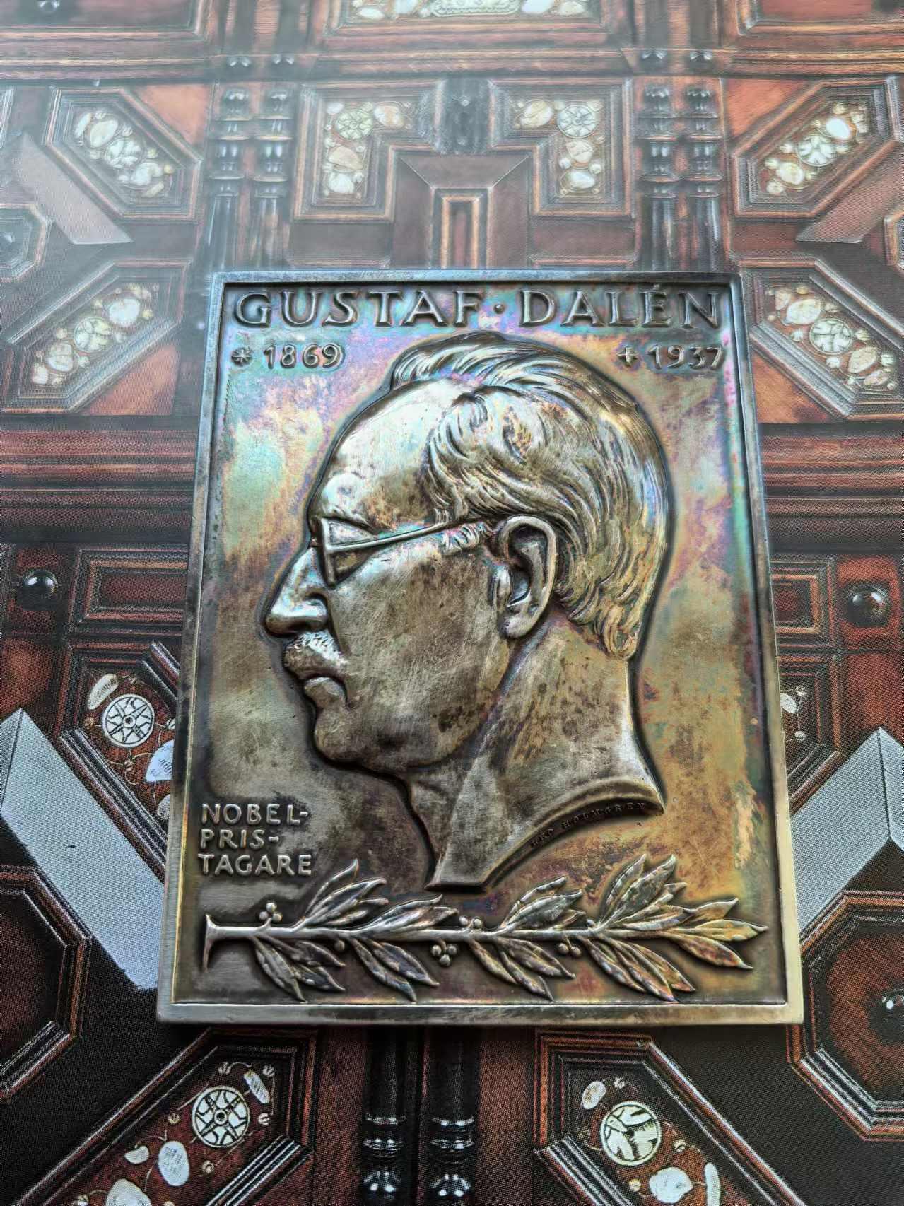 外国币章第二十五期 瑞典银章，5.5x7.5 cm，126g。Gustaf Dalén，1869年11月30日-1937年12月9日)，瑞典物理学家与发明家，研究领域为机械工程的应用。1912年因为发明结合燃点航标、燃点浮标和蓄电池等功能的自动调节装置而获得诺贝尔物理学奖。 本章正面是他的半身像，背面寓意他发现的光明照亮了地球。自带特制亚克力摆架，彩色包浆。