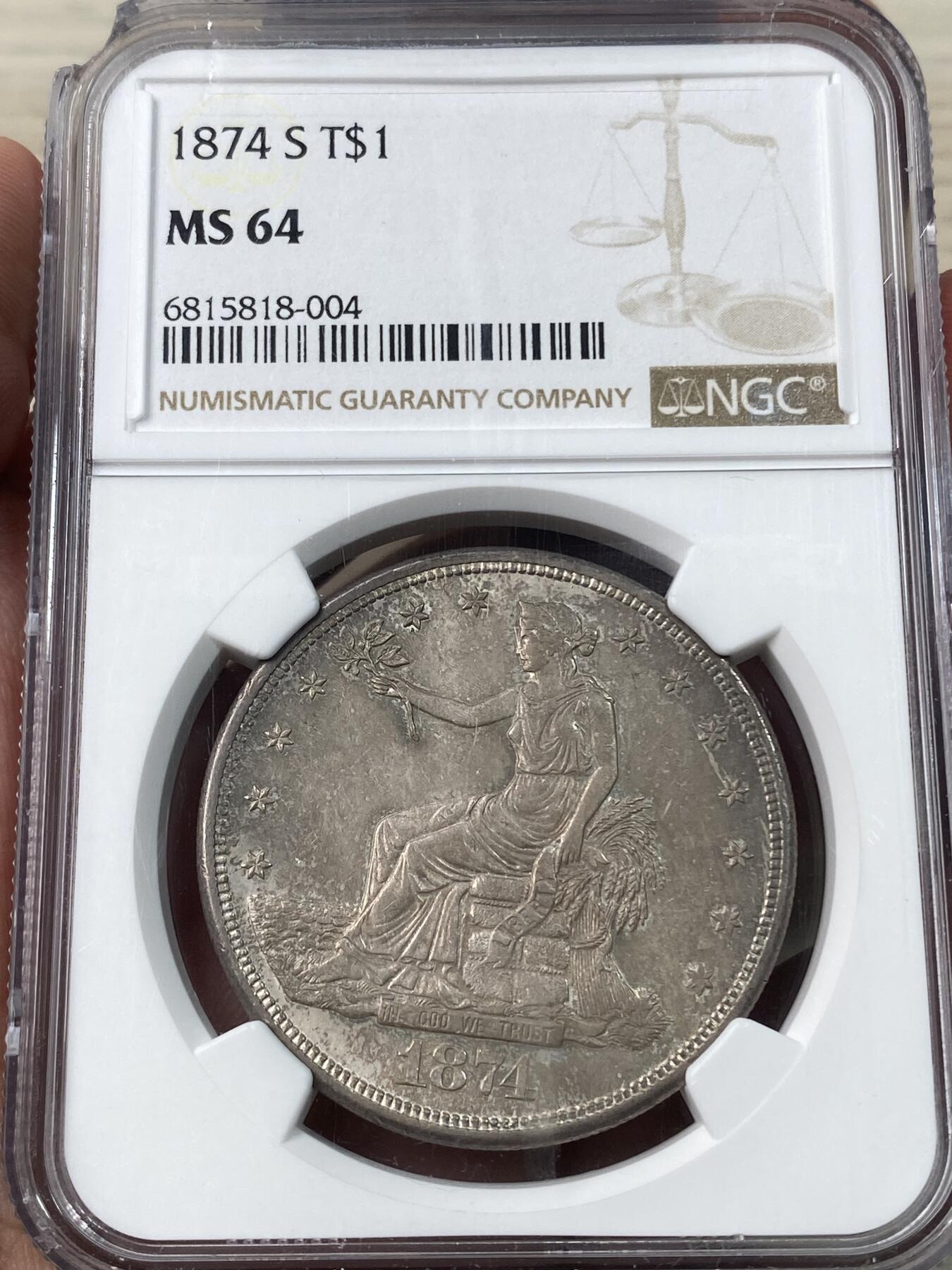 万国钱币拍卖第034期 NGC MS64 1874S美国拿花贸易银一元 曾在华广泛流通的贸易银品种，BU级别非常难得，双面均匀纸袋包浆，转光依旧，顶级收藏品相。（盒子左上角破损）
