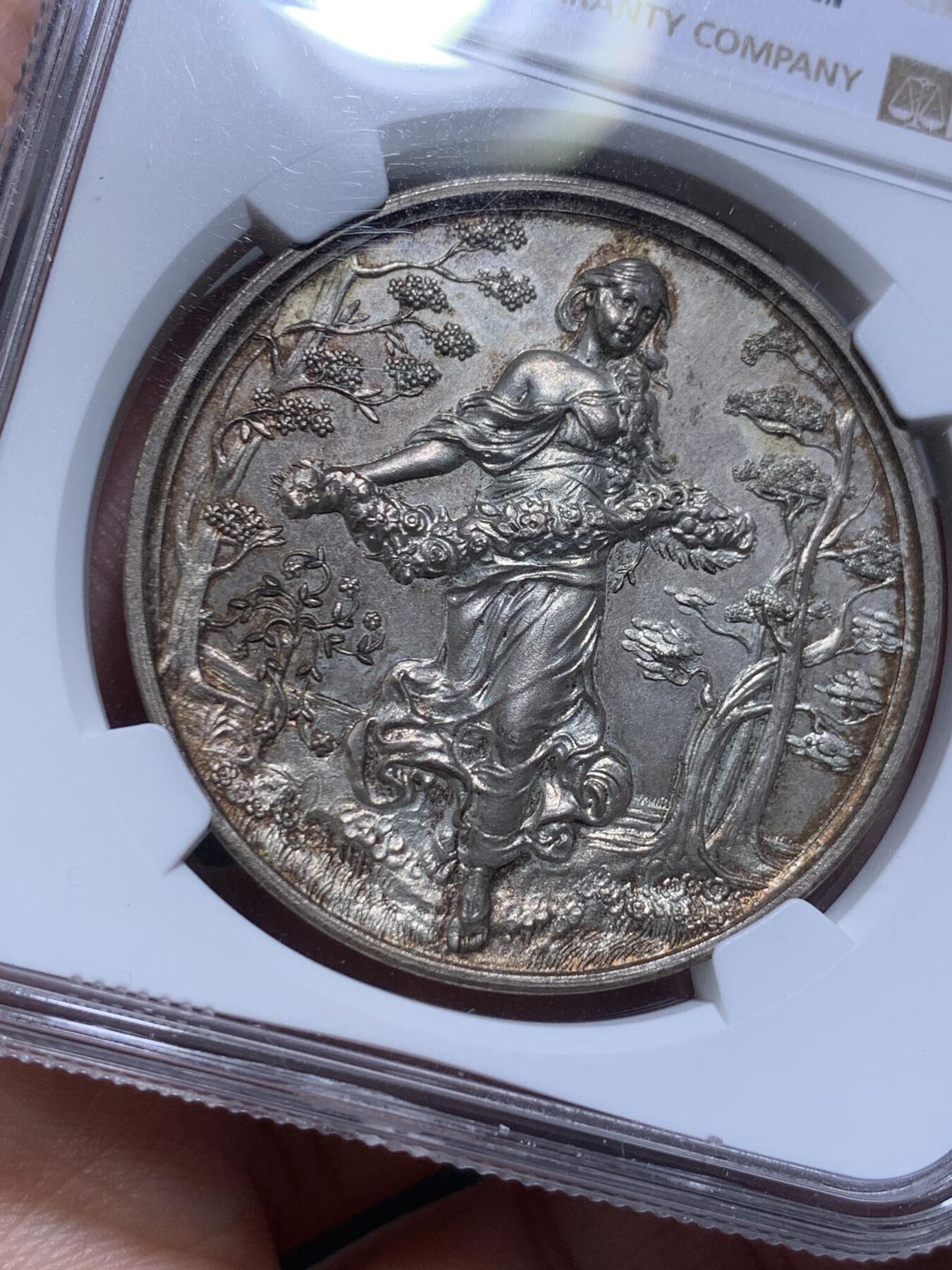 《竞宝斋》第315场 周日，周一，周二  3场连拍 （全场包邮） NGC MS64 稀见德国园艺镀银大铜章，Eoster女神手捧花环，赤脚悠然自得行走在软绵的草地中，迎风而来面带笑意，长发飘逸。深浮雕形象生动。MS64高分