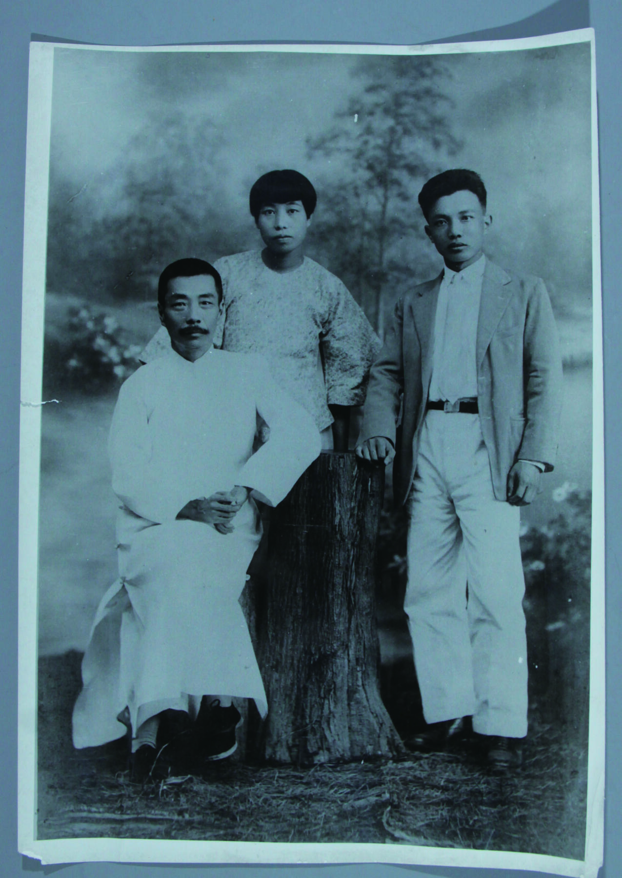 华宇2024年秋季拍卖会 1927年鲁迅许广平蒋经三合影照一张，尺寸：22×30CM，照片为鲁迅先生最经典的影像之一。1927年9月11日在广州中山大学任教的鲁迅与好友蒋经三以及与他刚刚交往不久的助教许广平。鲁迅将此事记入日记：“九月十一日。晴。下午蒋经三来同往艳芳照相，并邀广平。”照片中鲁迅先生身穿长衫，闲适地坐在椅子上，脸颊瘦削，双眼安然注视着前方。齐耳短发的许广平，站在他的身后，端庄而安静。此幅照片为新中国成立初期为