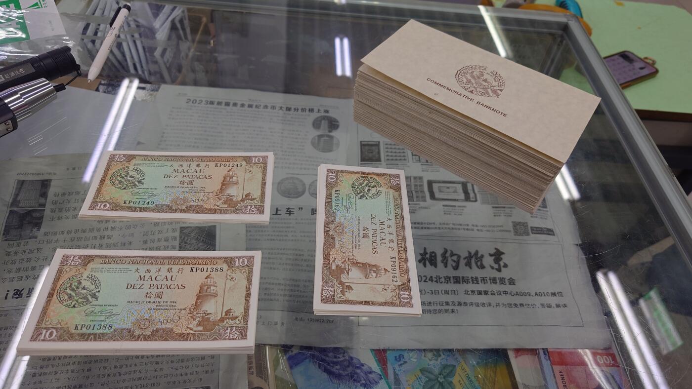 【世界钱币】精选微拍第151期暨2024年第63期～新到赛车钞群内卖剩货品选购～无胶水的几十张已经全部售罄，剩余的都有点轻微瑕疵 (预告11月底和12月上旬，12月中旬接连有币展新货群里卖剩款选购) 1988年澳门赛车纪念钞 全新UNC微瑕 号码无47尾号01385 (两个红圈处均有一块黄胶水印) 灯下无斑带原装册