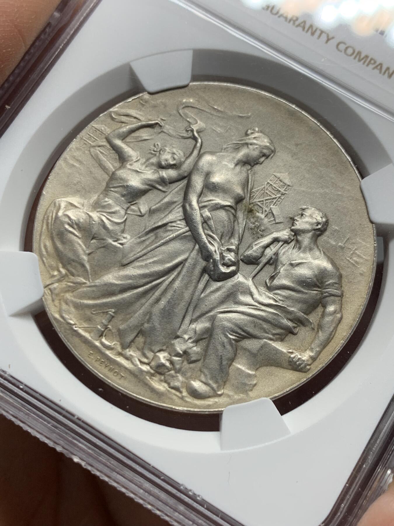《竞宝斋》第339场 周日，周一，周二 3场连拍 （全场包邮） NGC MS63 少见银质奖章。法国圣艾蒂安商会奖章。正面:矿工妻子，脚下一盏矿工灯，矿工坐在铁砧上，底部签名：E.PEYNOT 反面:锻造和采矿工具装饰