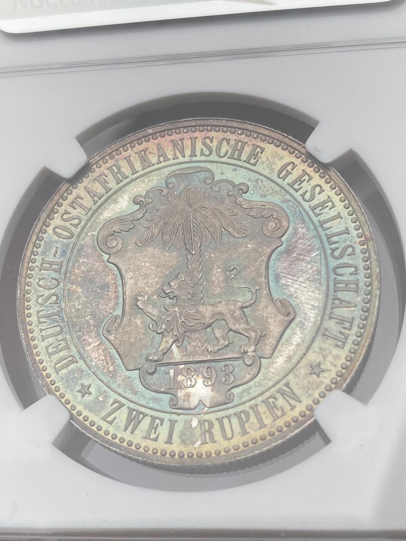 万国钱币拍卖第040期（万国2025新年大拍） NGC PF65 1893年德属东非威廉二世精制2卢比大银币  德属大名誉品种，德属东非领土总面积约为一百万平方公里，几乎是如今德国面积的三倍，普制高分已是难得一见，此等级别的精制已是另一个维度的存在，美到窒息的孔雀蓝彩，隔着盒子也能感受到其边齿的锋利程度，抛光镜面闪烁出的永恒之光让我们能一窥德意志帝国殖民时代的余晖，NGC唯一冠军。