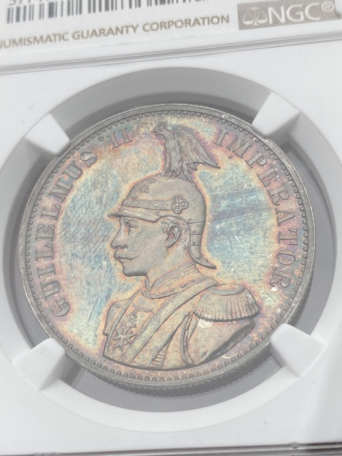 万国钱币拍卖第040期（万国2025新年大拍） NGC PF65 1893年德属东非威廉二世精制2卢比大银币  德属大名誉品种，德属东非领土总面积约为一百万平方公里，几乎是如今德国面积的三倍，普制高分已是难得一见，此等级别的精制已是另一个维度的存在，美到窒息的孔雀蓝彩，隔着盒子也能感受到其边齿的锋利程度，抛光镜面闪烁出的永恒之光让我们能一窥德意志帝国殖民时代的余晖，NGC唯一冠军。