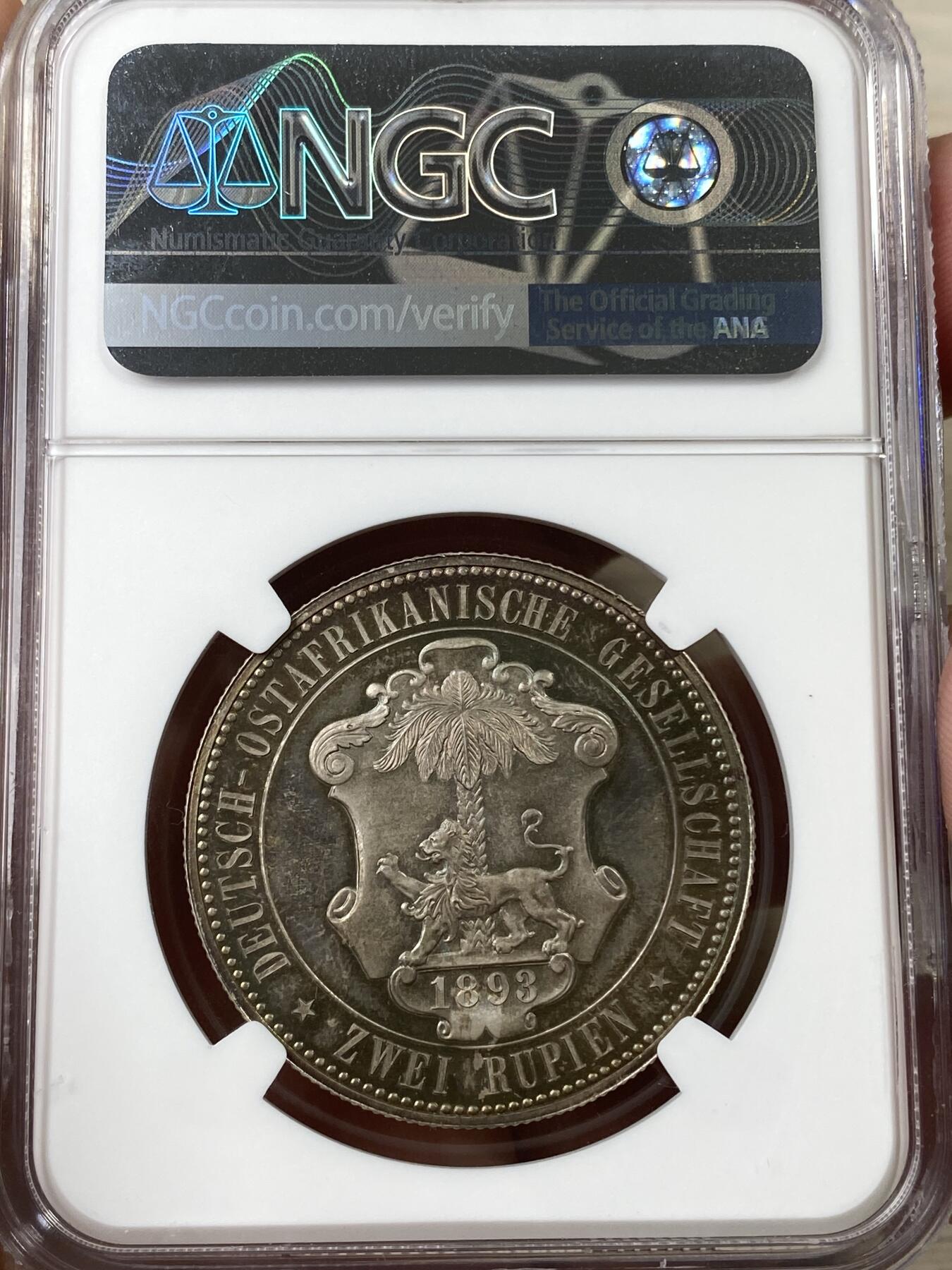 万国钱币拍卖第040期（万国2025新年大拍） NGC PF65 1893年德属东非威廉二世精制2卢比大银币  德属大名誉品种，德属东非领土总面积约为一百万平方公里，几乎是如今德国面积的三倍，普制高分已是难得一见，此等级别的精制已是另一个维度的存在，美到窒息的孔雀蓝彩，隔着盒子也能感受到其边齿的锋利程度，抛光镜面闪烁出的永恒之光让我们能一窥德意志帝国殖民时代的余晖，NGC唯一冠军。