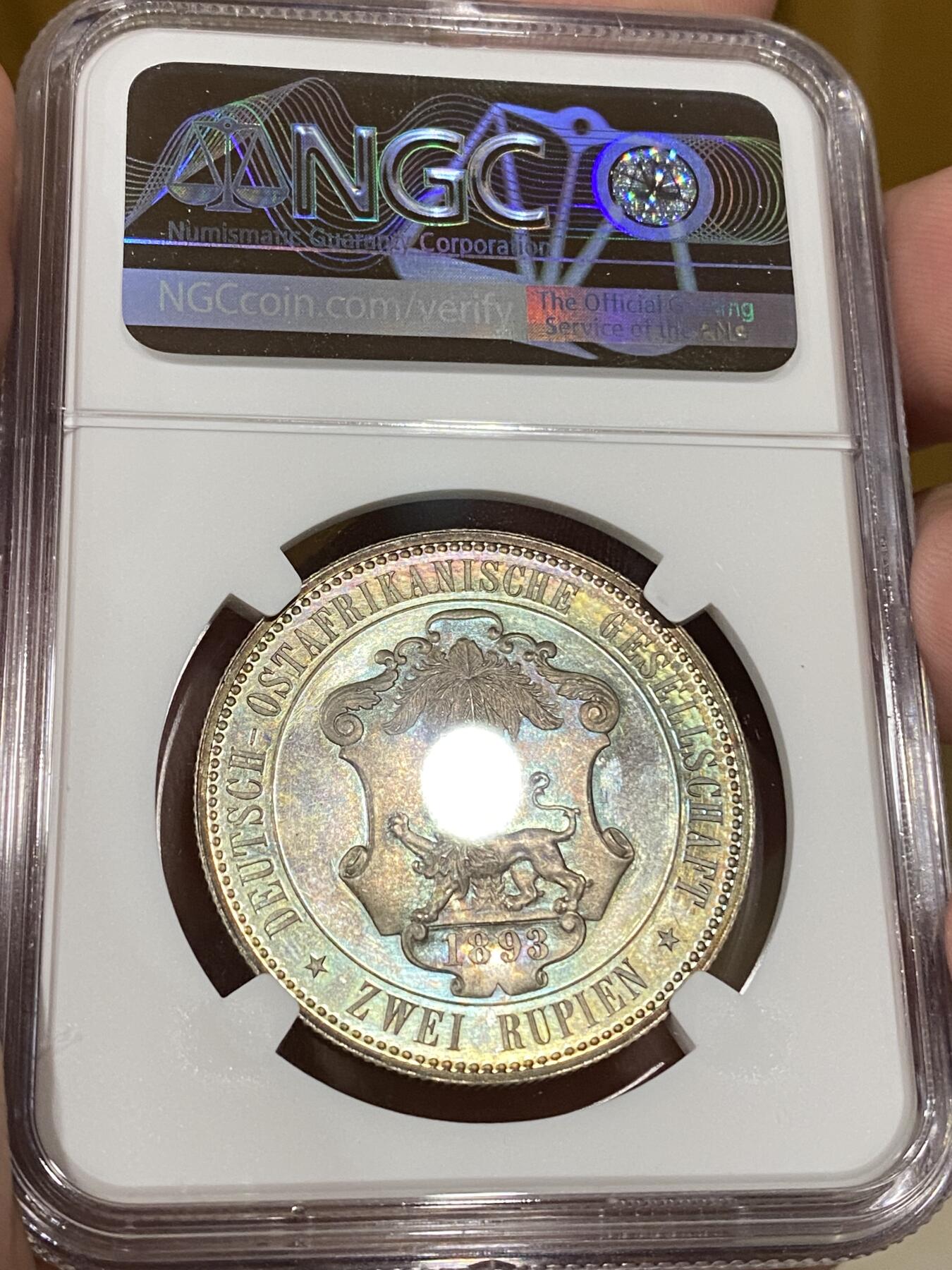 万国钱币拍卖第040期（万国2025新年大拍） NGC PF65 1893年德属东非威廉二世精制2卢比大银币  德属大名誉品种，德属东非领土总面积约为一百万平方公里，几乎是如今德国面积的三倍，普制高分已是难得一见，此等级别的精制已是另一个维度的存在，美到窒息的孔雀蓝彩，隔着盒子也能感受到其边齿的锋利程度，抛光镜面闪烁出的永恒之光让我们能一窥德意志帝国殖民时代的余晖，NGC唯一冠军。