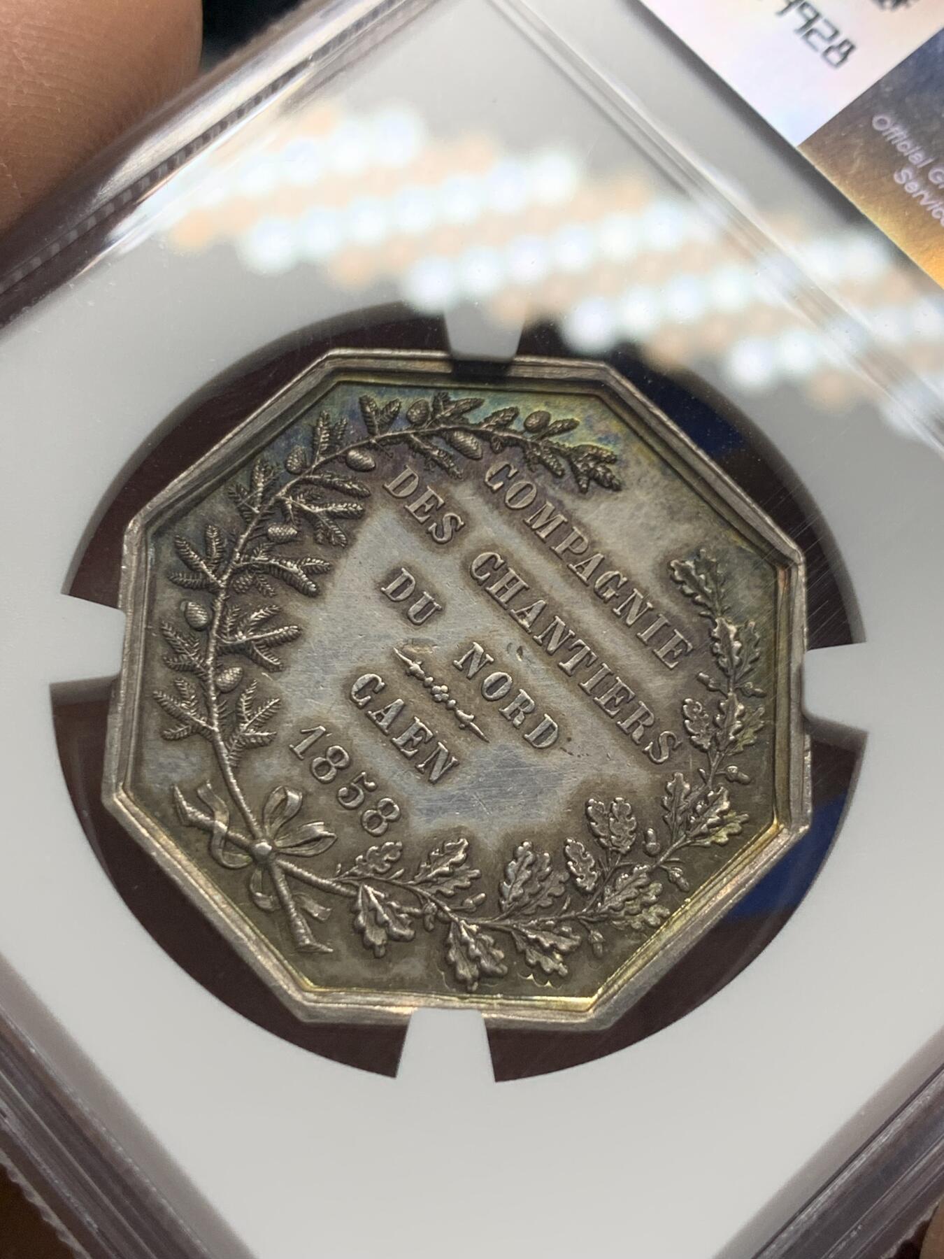 《竞宝斋》第348场 周日，周一，周二  3场连拍 （全场包邮） NGC MS62 首见品。诺曼底八边形银质代币，卡昂建筑公司。正面：商业女神站在左边，手托丰饶的角和一个caduceus，在造船厂前面，右边是一艘航行的船只；签名F下方。博斯坎卡昂。直径：31mm、重：14.17g