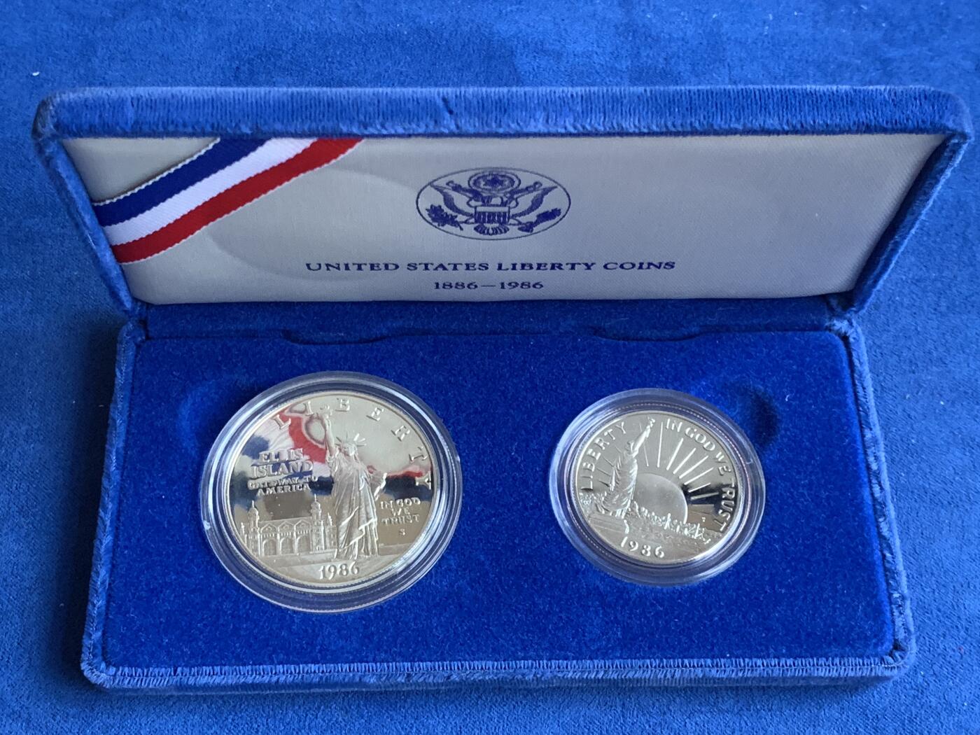 《竞宝斋》第353场 周日，周一，周二 3场连拍 （全场包邮） 美国1986年纪念自由女神像建成100周年精制银币套装。银币正面为庄严肃穆自由女神像，银币反面为自由女神像的火炬以及诗歌《新巨人》中的文字。 半美元铜镍币正面为纽约的天际线，自由女神像举起手臂，迎接一艘驶向纽约的班轮，太阳从东方升起，寓意着新世界新生活的开始。背面图案源自埃利斯岛上等待前往纽约的移民照片，反映了自由女神像作为移民希望象征的意义。