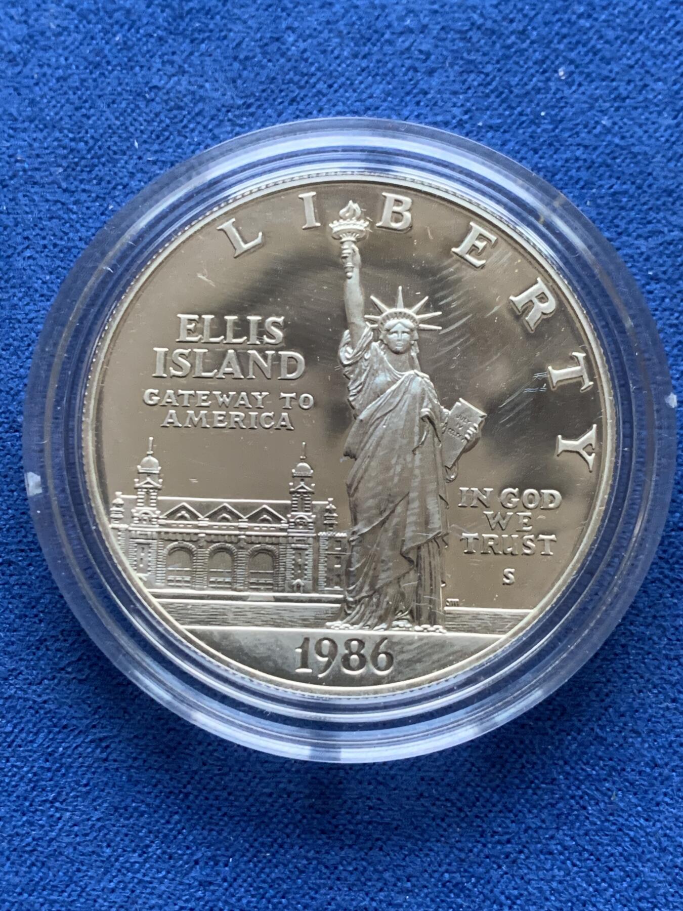 《竞宝斋》第353场 周日，周一，周二 3场连拍 （全场包邮） 美国1986年纪念自由女神像建成100周年精制银币套装。银币正面为庄严肃穆自由女神像，银币反面为自由女神像的火炬以及诗歌《新巨人》中的文字。 半美元铜镍币正面为纽约的天际线，自由女神像举起手臂，迎接一艘驶向纽约的班轮，太阳从东方升起，寓意着新世界新生活的开始。背面图案源自埃利斯岛上等待前往纽约的移民照片，反映了自由女神像作为移民希望象征的意义。