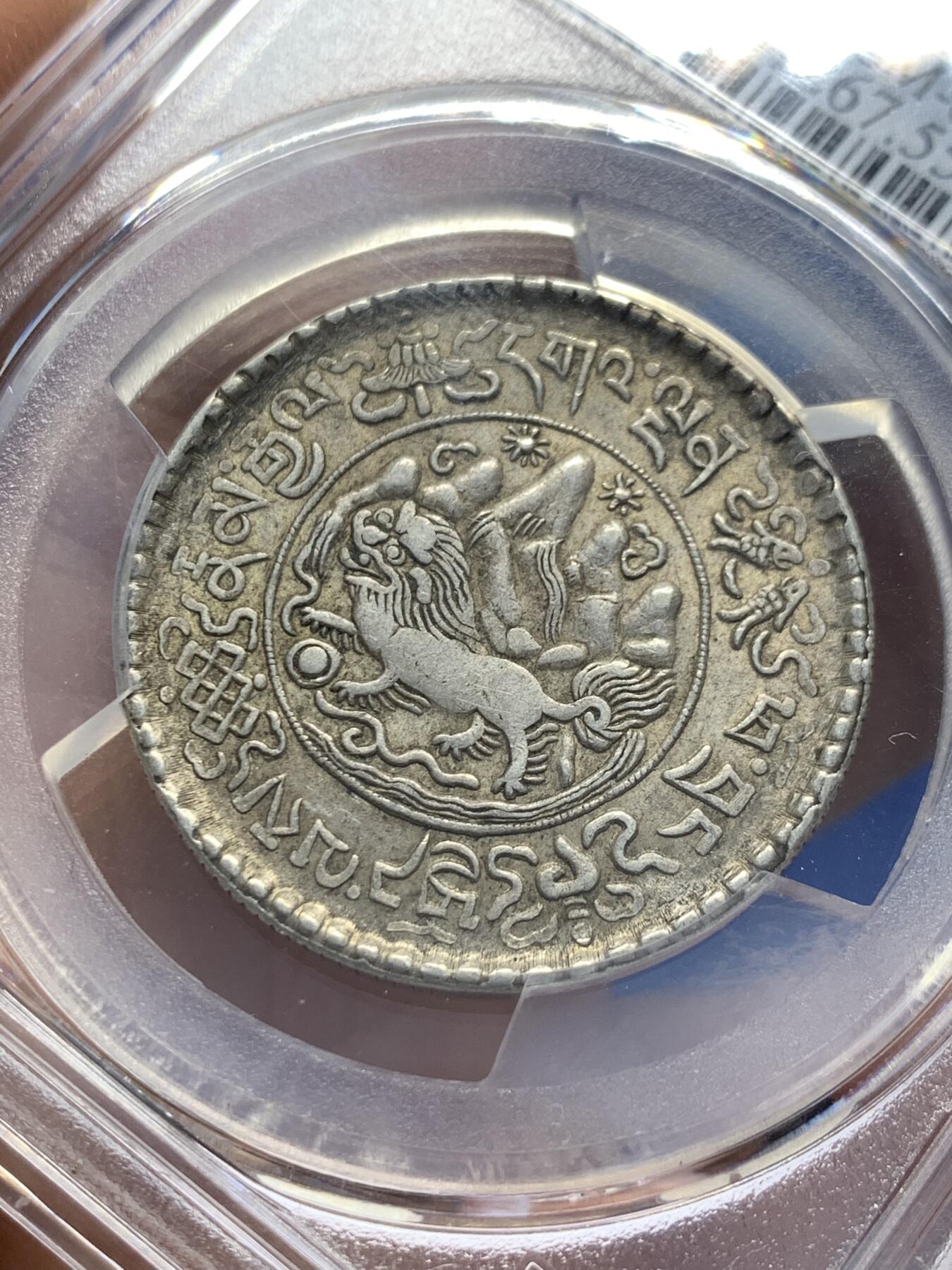 《竞宝斋》第353场 周日，周一，周二 3场连拍 （全场包邮） PCGS AU55 中国1937年西藏桑松果木三两银币，正面中央圆环内为日月、冈仁波齐雪山、祥云、狮子、绣球图案，外圈由宝伞（左上）、宝鱼（右上）、白海螺（右下）、吉祥结（左下）作为间隔环刻藏文“甘丹颇章，战胜四方”字样。背面中央圆环内为花枝和宝瓶图案，周围环绕缠枝纹和飘带；外圈以胜利幢（上）、金法轮（下）和莲花（左右）作为间隔，环刻藏文纪年、面值。具有独特的历史背景、文化内涵和艺术特征。此枚原味