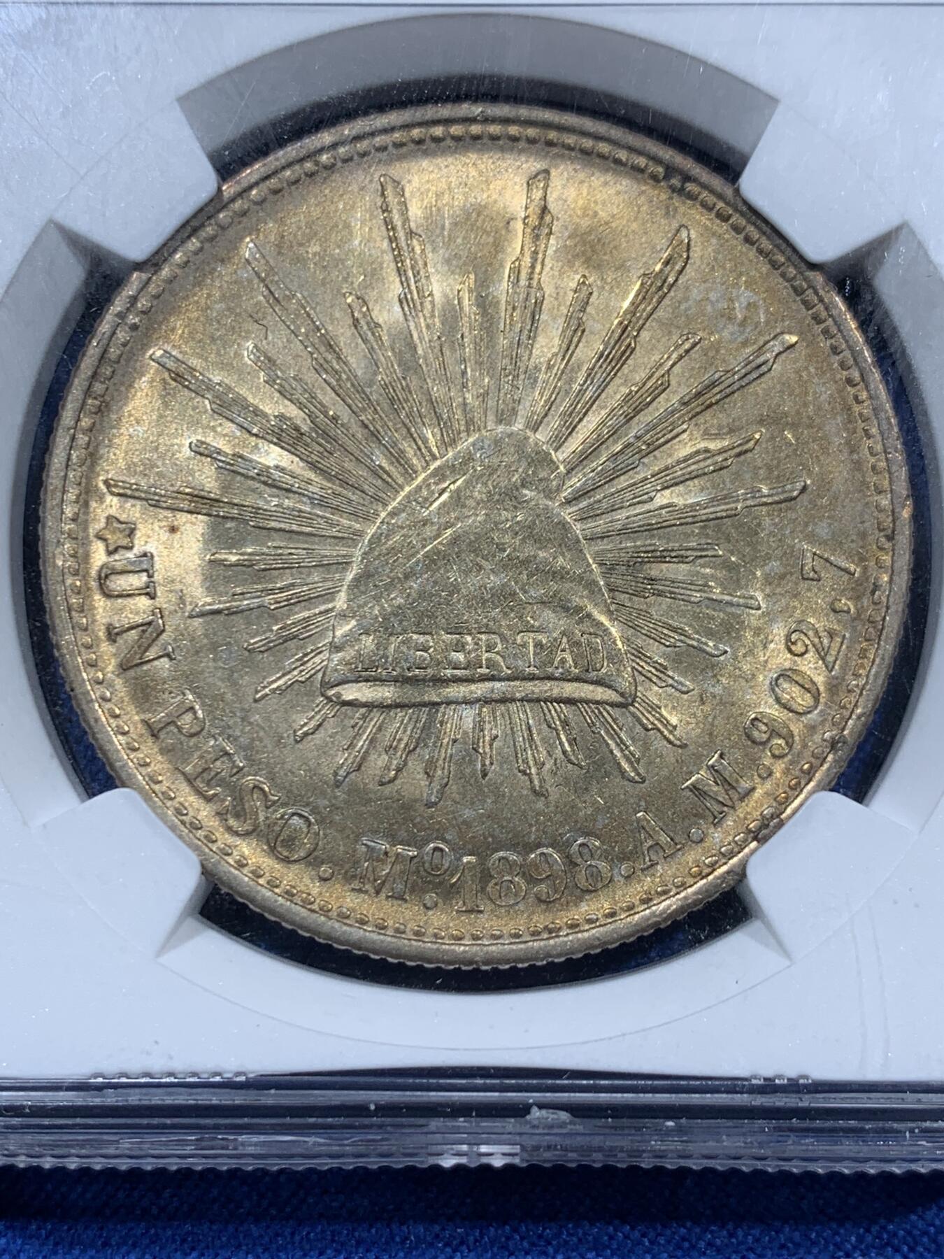 《竞宝斋》第360场 周日，周一  2场连拍 （全场包邮） NGC MS63 高分1898MO AM墨西哥1比索鹰洋，该版本为国民政府为作军饷而铸造在华流通，币面无磨损高点具在，鹰羽毛栩栩如生，非常好看的渐变黄油五彩包浆，转光感强烈，币面霜感由在，高分非常不易