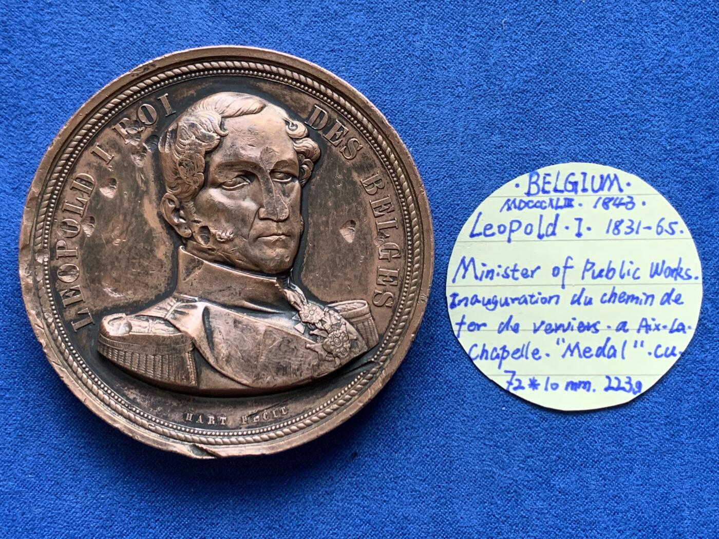 《竞宝斋》第360场 周日，周一  2场连拍 （全场包邮） 比利时王国1843年铁路开通纪念铜章，1843年（MDCCCXLIII）为纪念韦尔维耶至亚琛铁路开通而铸造发行的铜章，红铜材质，尺寸大而厚重，数据约为：72*7.5毫米，223.5克。正面：比利时第一代国王利奥波德一世。背面：手持盾牌象征“比法德”三国的希腊化女神像，下方2位手持酒罐和羽毛的希腊化男神像，两侧为商业之神墨丘利的双蛇权杖，背景图为火车通过的景观图。上方铭文大意“战争使人离散，和平让人