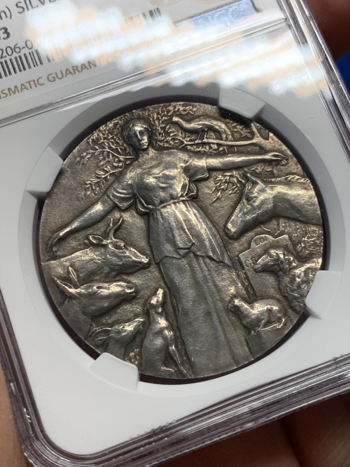 《竞宝斋》第361场 周日，周一  2场连拍 （全场包邮） NGC MS63 高分 首见品  动物保护协会铜镀银奖章。正面女神披着古老的披风，将她的手臂伸向聚集在她周围的动物身上，直径：39.5mm。
