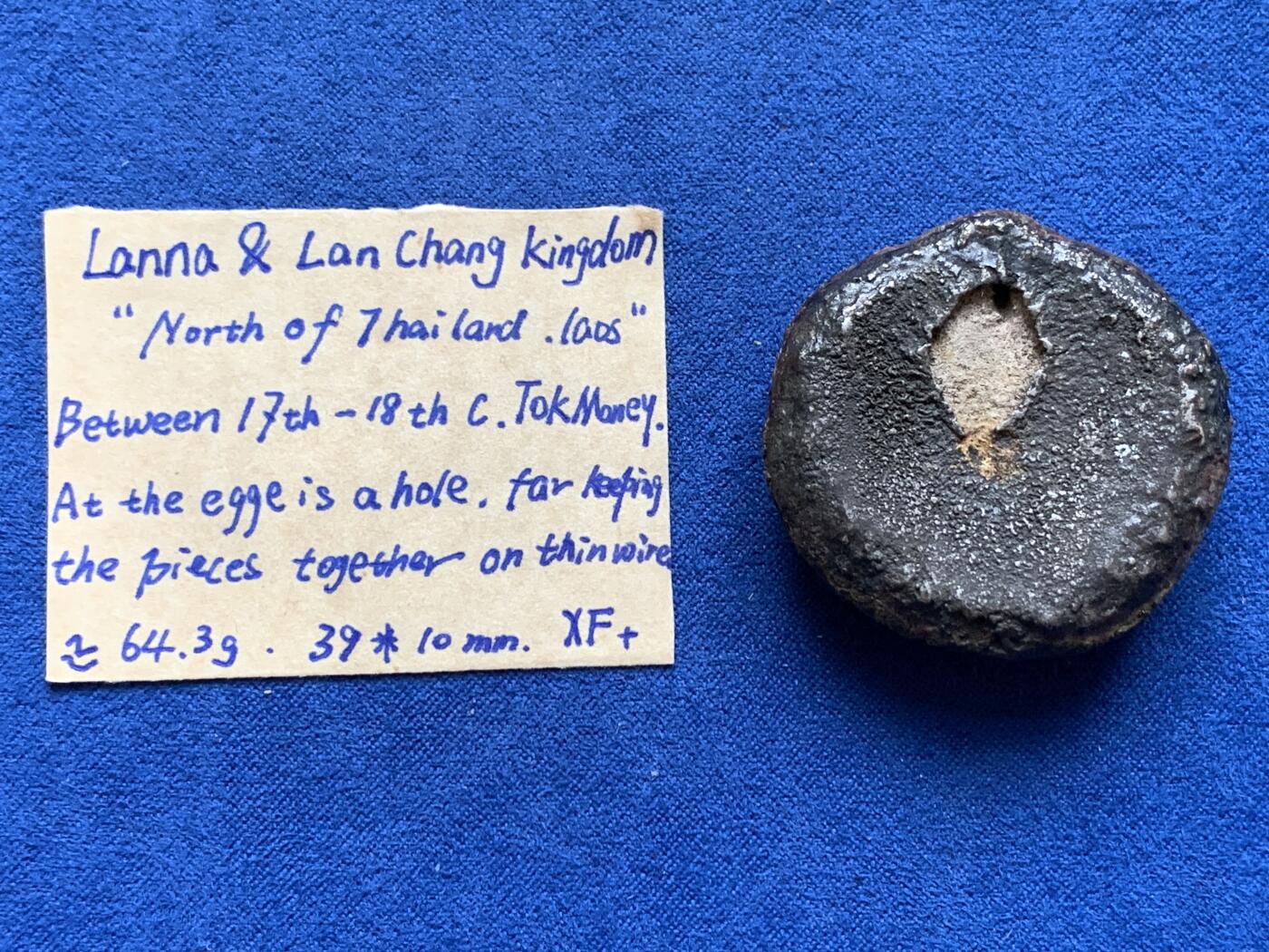 《竞宝斋》第370场 周日，周一 2场连拍 （全场包邮） 兰纳.澜沧王国托克银锭 17至18世纪铸行于兰纳和澜沧王国(今泰北及老挝)，先在半圆形模具中浇铸后在铸锭边缘打孔以便于穿串保存使用。重约64.3克，36.8*10毫米。相当于同时期泰南4铢银以及云南2两银锭！该类通常顶部呈银黑色，底部呈黄棕及红色，这种情况归因于银合金中少量硫化物析出及脱模剂残留。此枚较同品种而言已算高银，近未使用品，包浆浑厚，底部残留原始银光和脱模痕。