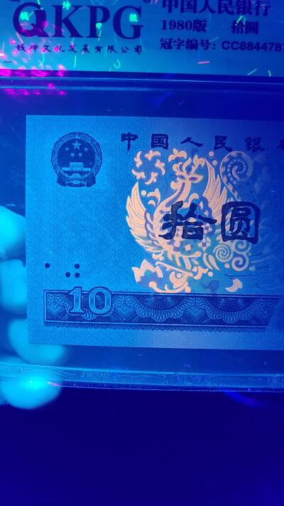 周六拍场，纸币、古币、邮票 钱坤评级8010—双冠，荧光编码。CC88447874   灯下满版金凤凰荧光，由于送评较早，当时满版金凤凰还没有开标，所以没有标注，灯下说明一切