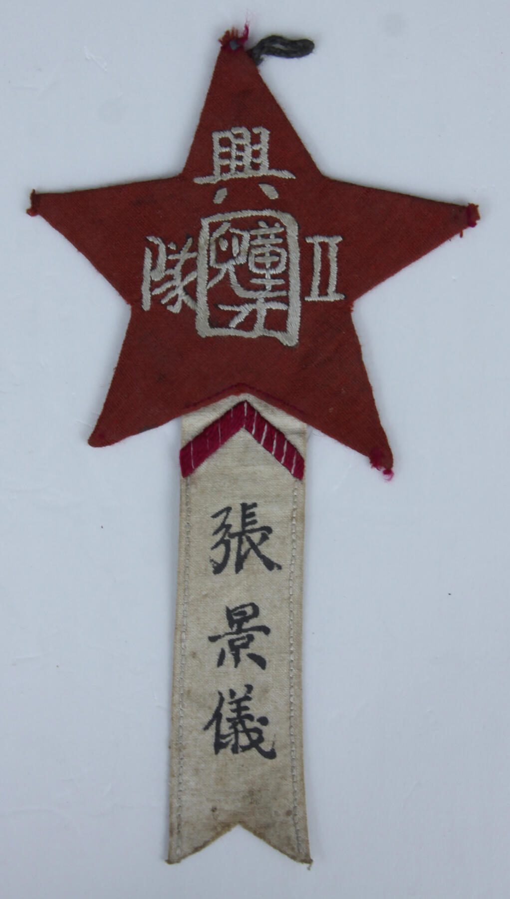 华宇2025年春季拍卖会 （馆藏）土地革命时期江西兴国县儿童队长景仪胸标一枚，尺寸：10×17CM.兴国是全国著名的苏区模范县、红军县、烈士县和誉满中华的将军县。毛泽东、朱德、周恩来、陈毅等老一辈无产阶级革命家都曾在这里工作和战斗过。苏区时期，全县23万人口，参军参战的就达8万多人，为国捐躯的达5万多人，全县姓名可考的烈士达23179名，长征路上几乎每一公里就有一名兴国籍将士倒下。在血与火的考验中，孕育了肖华、陈奇涵等56