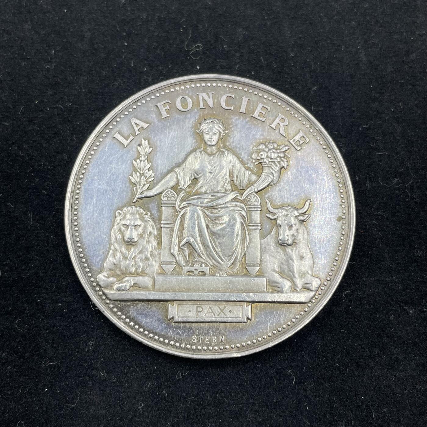 「木头集藏」章牌专场-第56场 法国土地保险公司银章  直径：37mm，22.8 g，  边铭：丰饶角 ARGENT  正面刻画玛丽安娜端坐在宝座上，左手持月桂枝，代表胜利与荣誉；右手环保丰饶角，象征繁荣富足，两侧分别卧着狮子与牛，代表权威、勤劳。