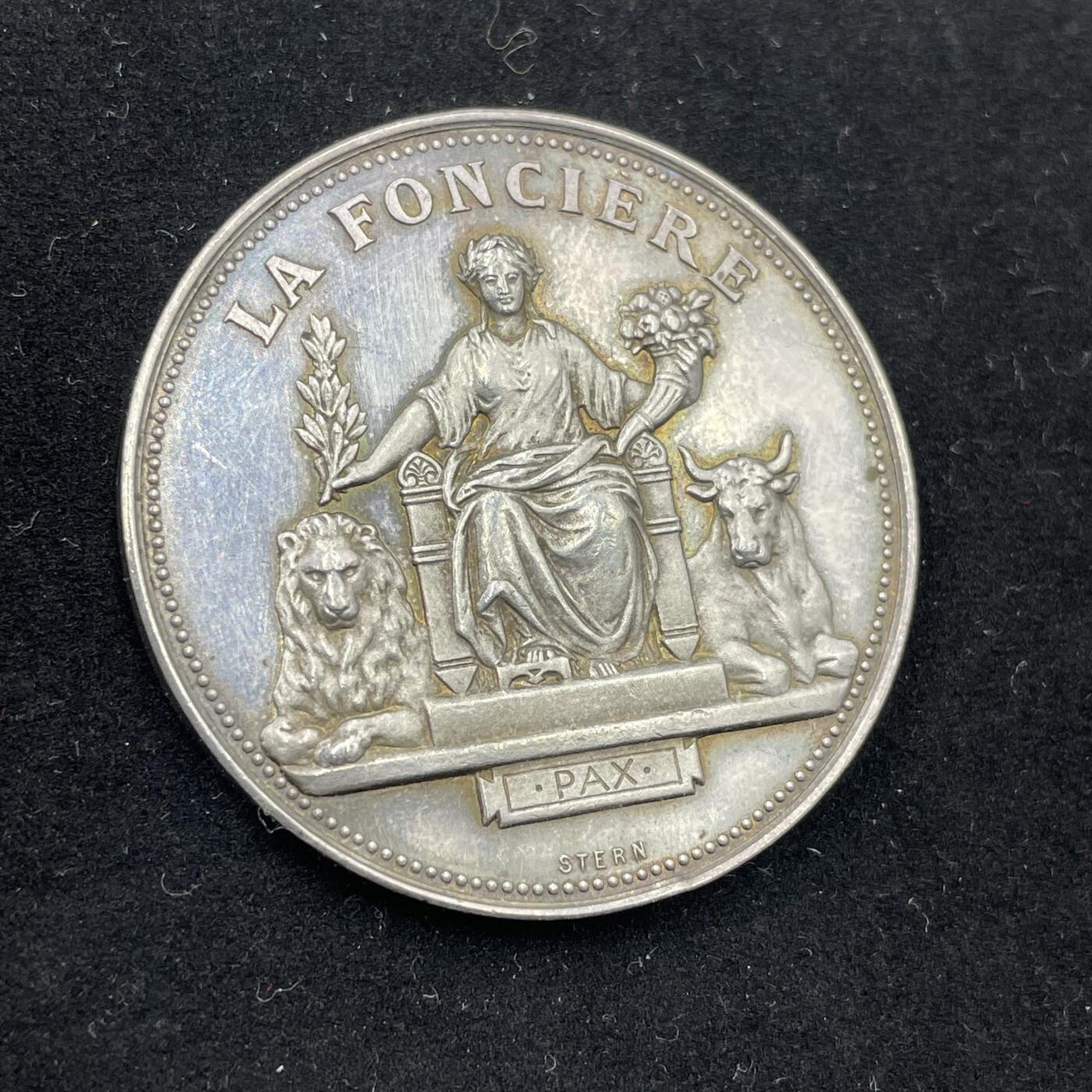 「木头集藏」章牌专场-第56场 法国土地保险公司银章  直径：37mm，22.8 g，  边铭：丰饶角 ARGENT  正面刻画玛丽安娜端坐在宝座上，左手持月桂枝，代表胜利与荣誉；右手环保丰饶角，象征繁荣富足，两侧分别卧着狮子与牛，代表权威、勤劳。