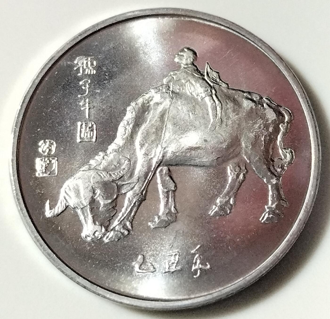 1985年春晚纪念章！1985年中央电视台春节晚会纪念章,为上海六一四造币厂制造一面是一幅儿童戏牛图，上面题着“孺子牛”三个字，下面注有“乙丑年”字样。从整体上看，其质量与现在发行的那些银光闪烁的纪念币比起来，显得很不一样，特别突出！按图发货！