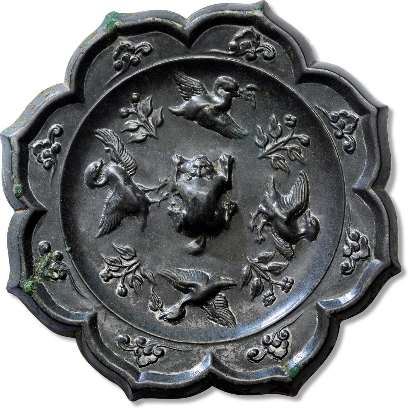上海匡时2025年春季拍卖会 四禽镜，直径：14cm，厚：1cm，重：687.1g，八出菱花形，伏兽钮。采用高浮雕的表现技法，纹饰分为内外两区。内区主纹饰为四禽同向相间环绕镜钮，追逐嬉戏，四禽造型生动，栩栩如生，一派祥和之气。四禽之间点缀四组花卉纹，镜缘处八瓣内环饰一周祥云纹饰。此镜胎体厚重，画面动感极强，纹饰十分有力度。整体光气一流，铸造精良，生动华丽。