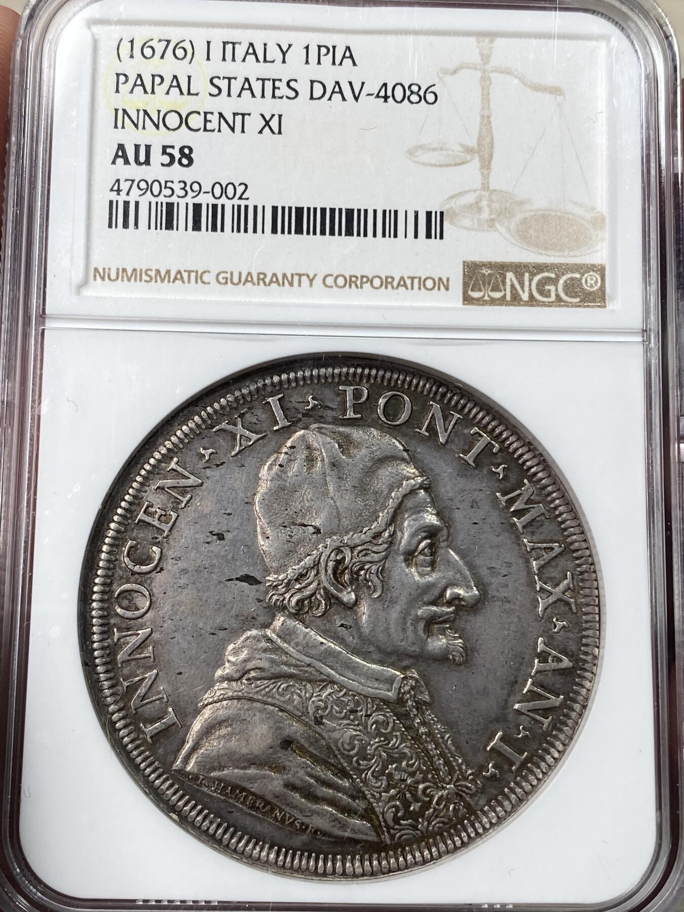 万国钱币拍卖第049期（万国夏季大拍） NGC AU58 1676年意大利教皇国因诺森十一世1皮阿斯特大银，正面为身着繁复华丽教宗服饰的因诺森十一世，背面为拿着书本的圣马太和天使，早期教皇国任何大银都极其昂贵，58已是佼佼者。此枚灰黑色均匀包浆，打制深峻，教皇国玩家不容错过。