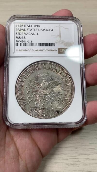 万国钱币拍卖第049期（万国夏季大拍） NGC MS63 1676年意大利教皇国缺位1皮阿斯特大银，教皇国缺位系列大银中最经典的品种。正面为火焰中散发着光芒的圣鸽，背面为帕鲁佐·帕鲁齐·阿尔贝托尼·阿尔蒂埃里的教会徽章。NGC亚军分，冠军为今年意大利拍出的65分，7000欧落槌，到手约合人民币7万。亚军63分一共5枚，其中三枚均出自一位中国收藏家，第四枚在HA派拉蒙集藏拍出，仅有一枚出处未知，来源清晰，数量稀少。