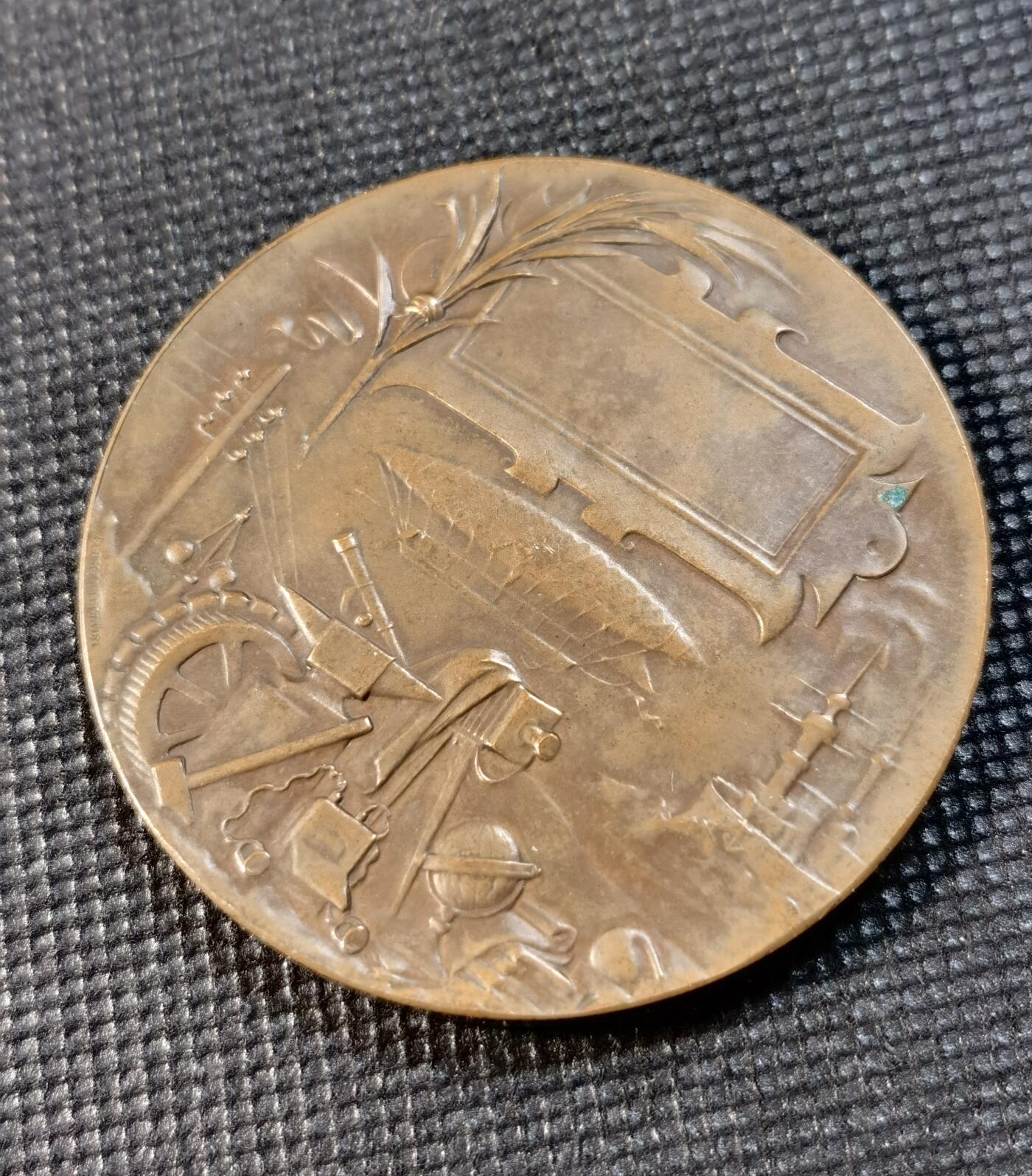  甄臻铺-世界币章拍卖（第24期），送拍享返佣金等优惠多多 1900年巴黎世界博览会纪念铜章，由Georges Lemaire大师设计制作。正面是胜利女神雕像，手持橄榄枝，象征和平与繁荣。背面是工业成就和科技发展的浮雕图案，包括蒸汽机车、望远镜等象征物。重量：63.765克，直径约54.1毫米，丰饶角BRONZE边铭。铜质厚重，雕工精美，保存状态良好。这枚珍贵的博览会纪念章，是19世纪末法国工业革命的重要见证