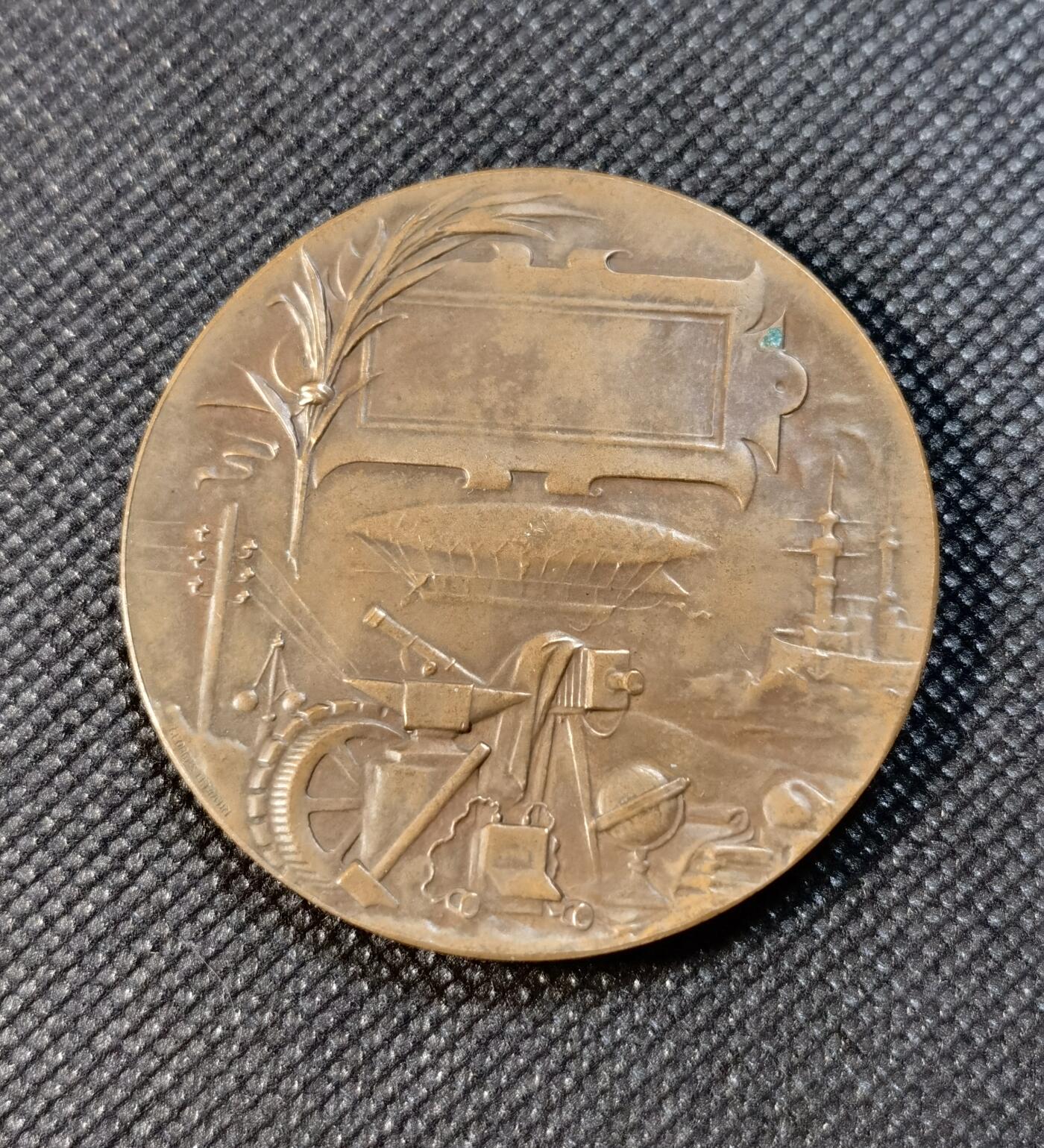  甄臻铺-世界币章拍卖（第24期），送拍享返佣金等优惠多多 1900年巴黎世界博览会纪念铜章，由Georges Lemaire大师设计制作。正面是胜利女神雕像，手持橄榄枝，象征和平与繁荣。背面是工业成就和科技发展的浮雕图案，包括蒸汽机车、望远镜等象征物。重量：63.765克，直径约54.1毫米，丰饶角BRONZE边铭。铜质厚重，雕工精美，保存状态良好。这枚珍贵的博览会纪念章，是19世纪末法国工业革命的重要见证