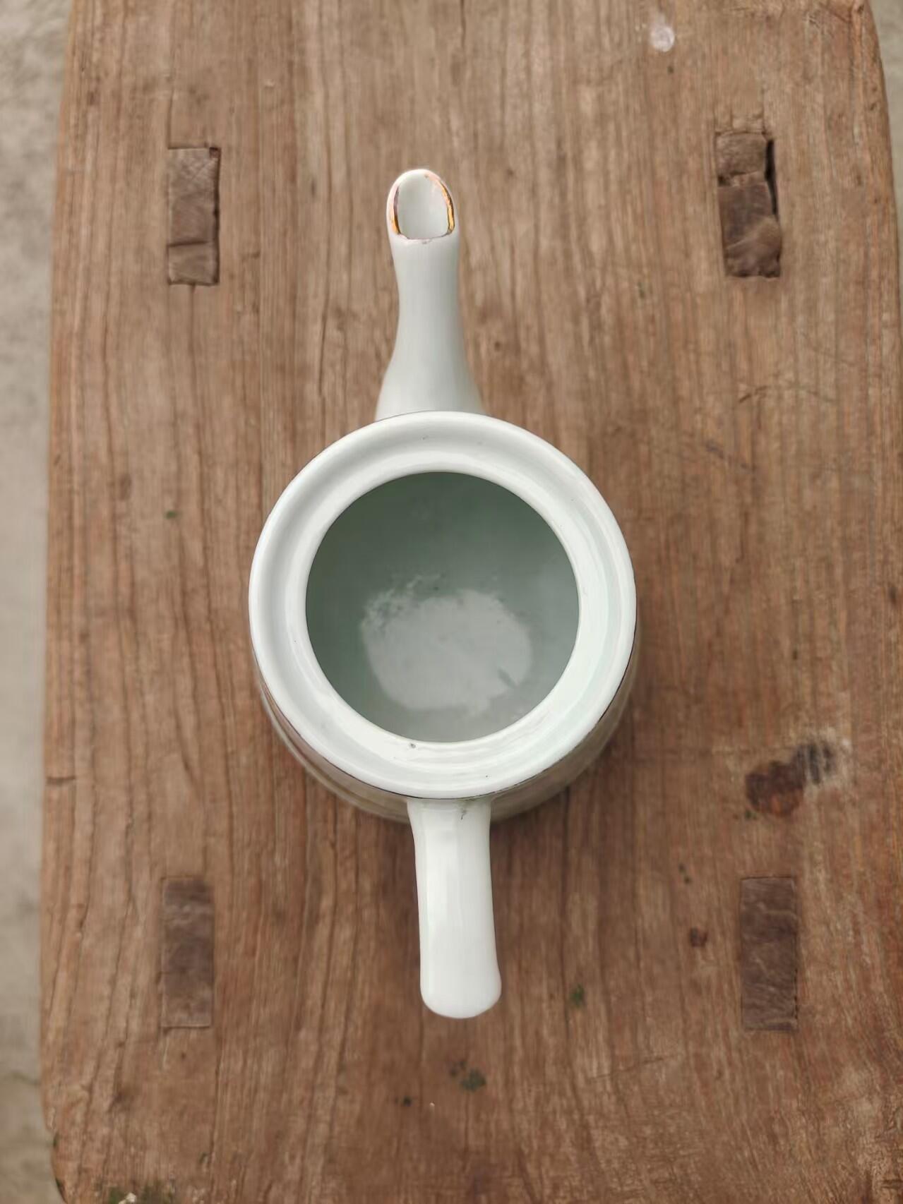 六七十年代手绘茶水壶一把 画工精美，瓷质细腻，壶身绘制山水风景图案，上有"团结 紧张 严肃 活泼"字样，口沿描金，尺寸约10厘米高，完整漂亮适合收藏或日常使用。