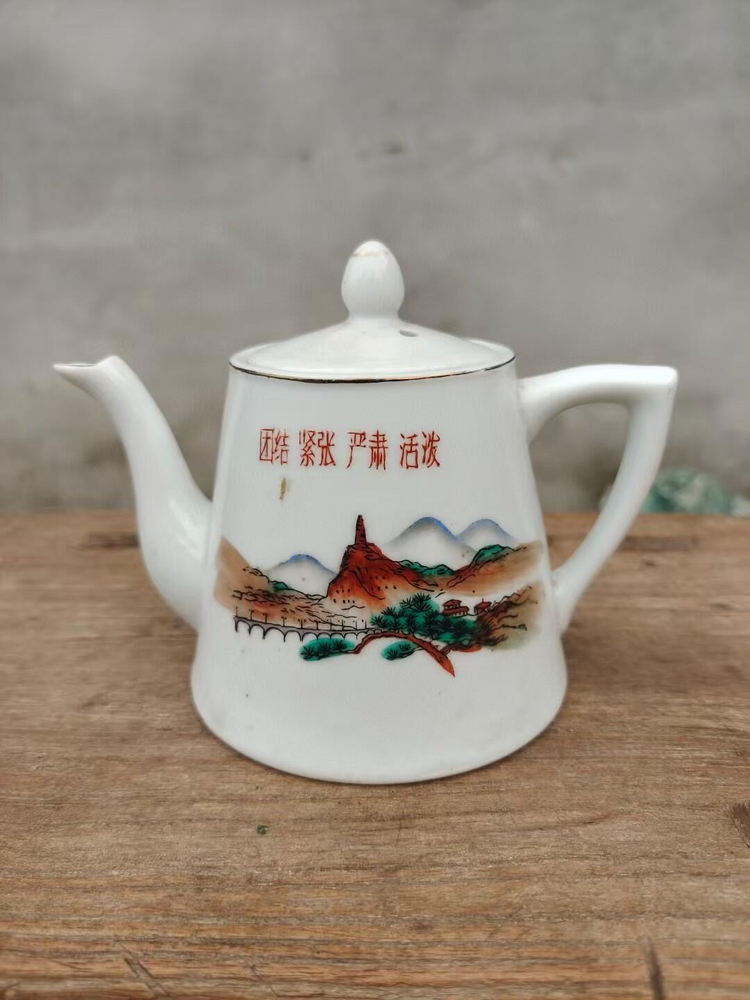 六七十年代手绘茶水壶一把 画工精美，瓷质细腻，壶身绘制山水风景图案，上有"团结 紧张 严肃 活泼"字样，口沿描金，尺寸约10厘米高，完整漂亮适合收藏或日常使用。