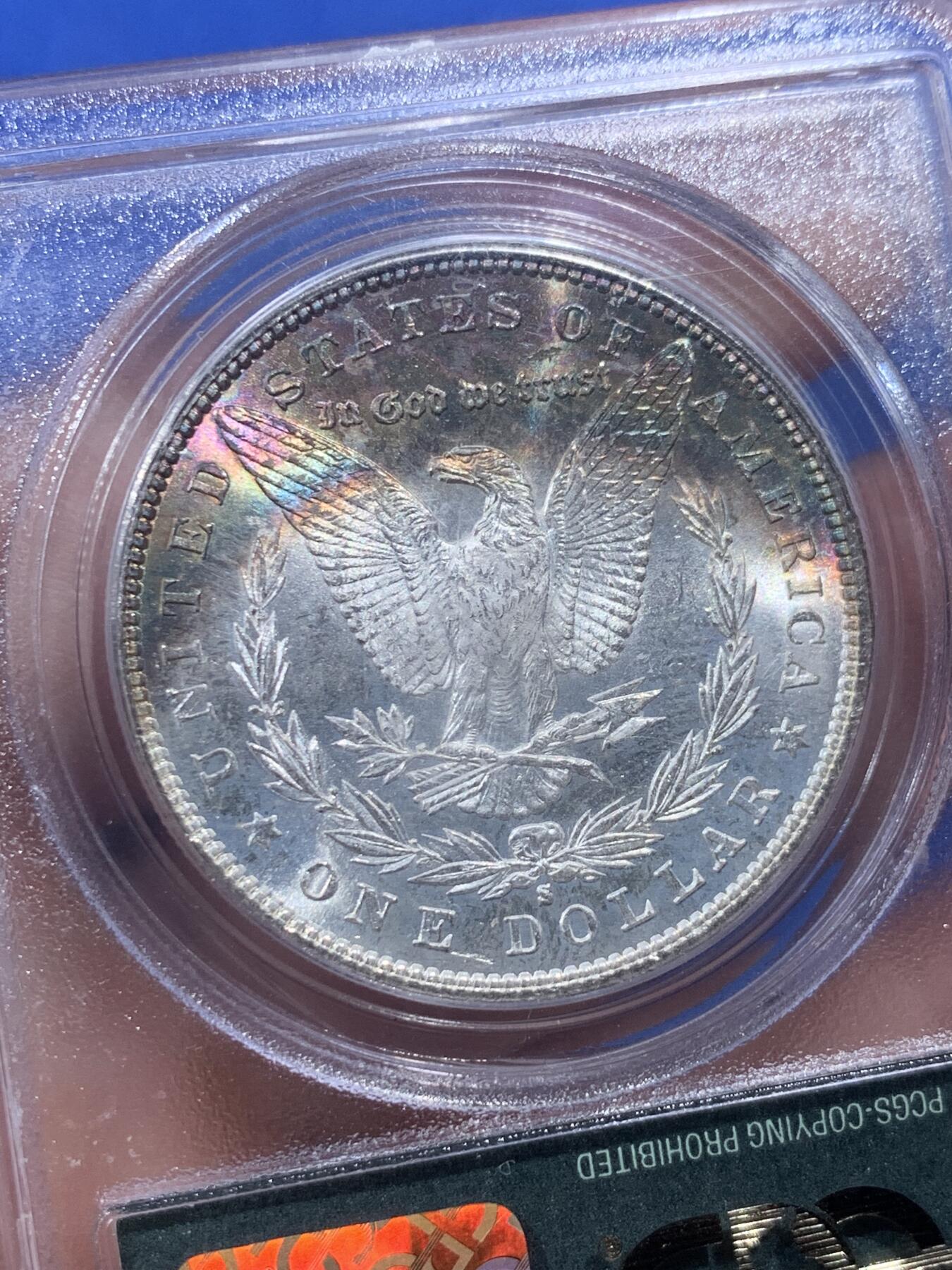《竞宝斋》第405场 周日，周一，2场连拍 （全场包邮） PCGS MS65 美国1881年S版摩根1美元银币 人面打制完整 光感一流 鹰面超大月牙五彩包浆 由外向内光彩各异 堪称一绝 月牙彩是很受摩根玩家追捧的包浆之一 此枚更是大面积 高分数 深绿色渐变为粉色 十分难得 不容错过