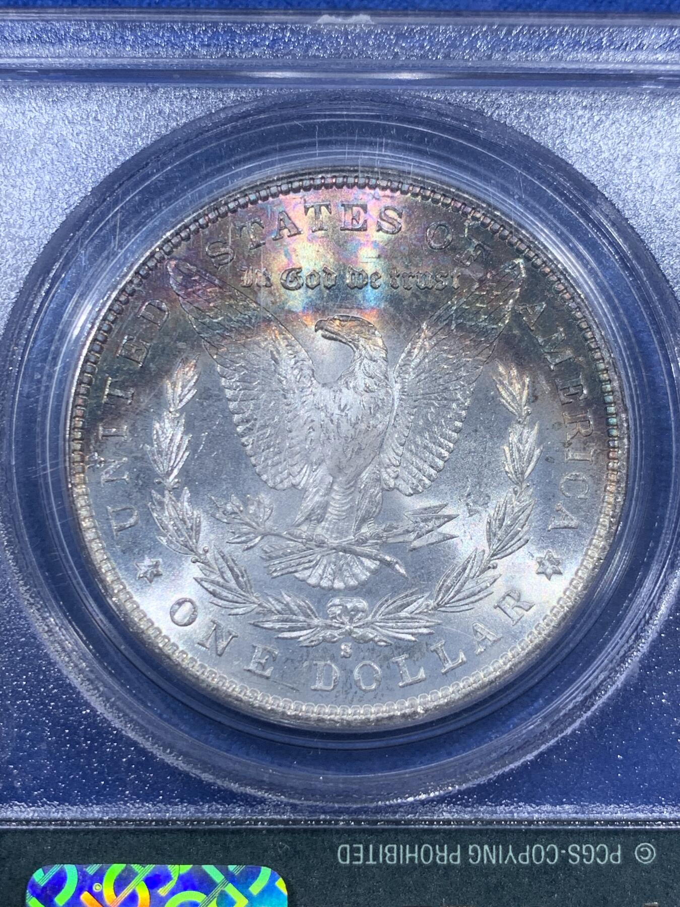 《竞宝斋》第405场 周日，周一，2场连拍 （全场包邮） PCGS MS65 美国1881年S版摩根1美元银币 人面打制完整 光感一流 鹰面超大月牙五彩包浆 由外向内光彩各异 堪称一绝 月牙彩是很受摩根玩家追捧的包浆之一 此枚更是大面积 高分数 深绿色渐变为粉色 十分难得 不容错过