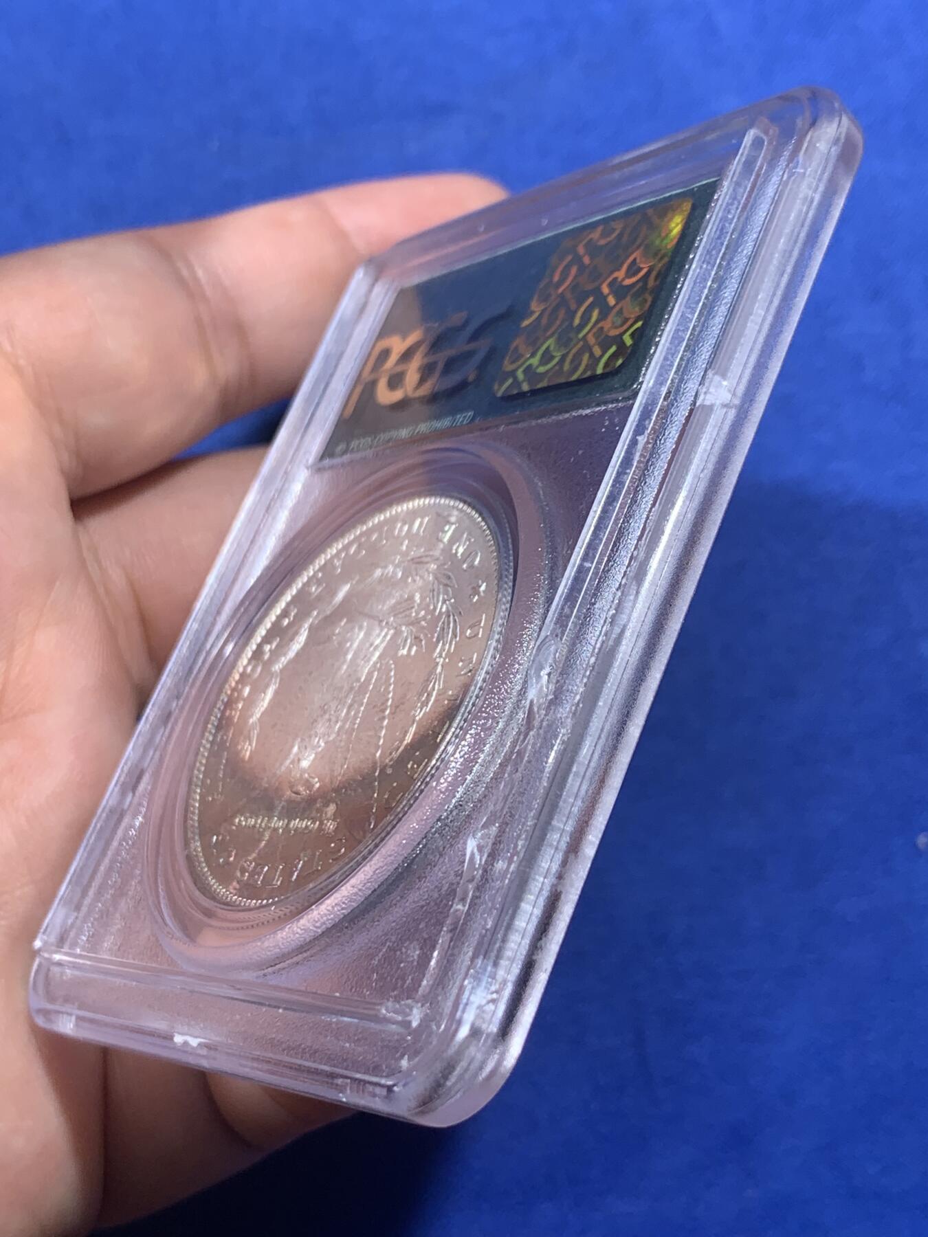 《竞宝斋》第405场 周日，周一，2场连拍 （全场包邮） PCGS MS65 美国1881年S版摩根1美元银币 人面打制完整 光感一流 鹰面超大月牙五彩包浆 由外向内光彩各异 堪称一绝 月牙彩是很受摩根玩家追捧的包浆之一 此枚更是大面积 高分数 深绿色渐变为粉色 十分难得 不容错过