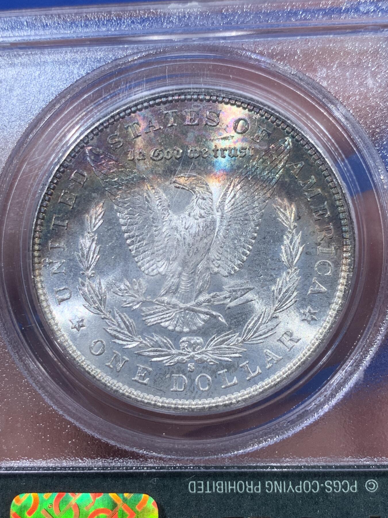 《竞宝斋》第405场 周日，周一，2场连拍 （全场包邮） PCGS MS65 美国1881年S版摩根1美元银币 人面打制完整 光感一流 鹰面超大月牙五彩包浆 由外向内光彩各异 堪称一绝 月牙彩是很受摩根玩家追捧的包浆之一 此枚更是大面积 高分数 深绿色渐变为粉色 十分难得 不容错过