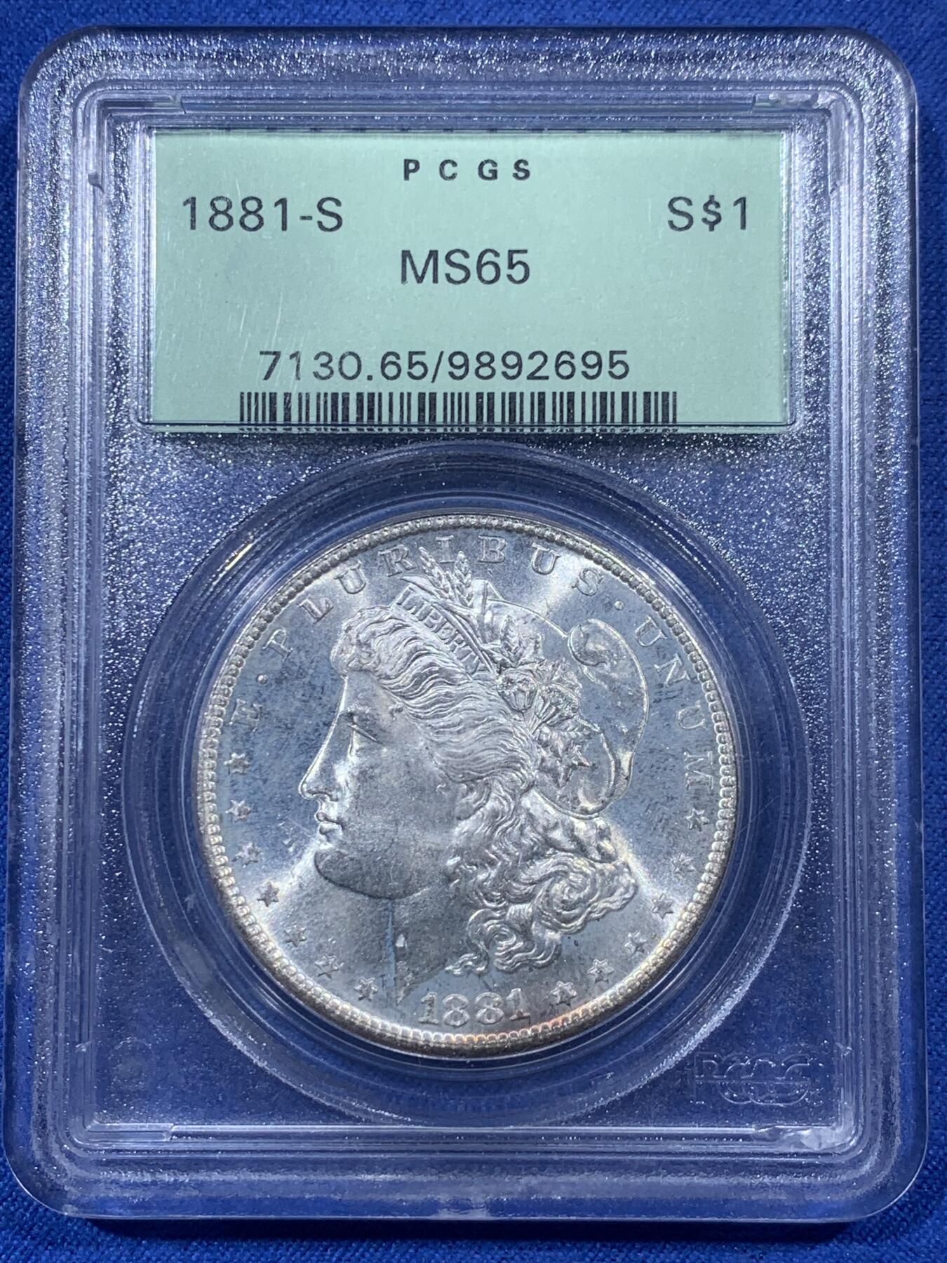 《竞宝斋》第405场 周日，周一，2场连拍 （全场包邮） PCGS MS65 美国1881年S版摩根1美元银币 人面打制完整 光感一流 鹰面超大月牙五彩包浆 由外向内光彩各异 堪称一绝 月牙彩是很受摩根玩家追捧的包浆之一 此枚更是大面积 高分数 深绿色渐变为粉色 十分难得 不容错过