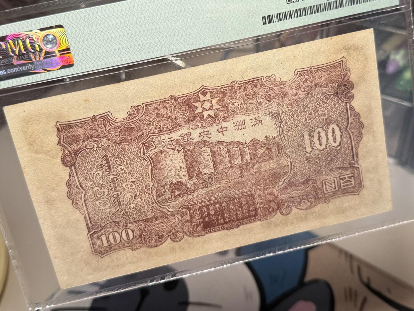 【乾奕收藏】出民国33年1944年满洲中央银行百圆，正面孔子大殿，背面粮仓图案，美国PMG58分，号码全程无47，民国纸币经过80年能保存如此品相实属难得，喜欢的老板不要错过，评级币一切以分数为准，售出非假不退 